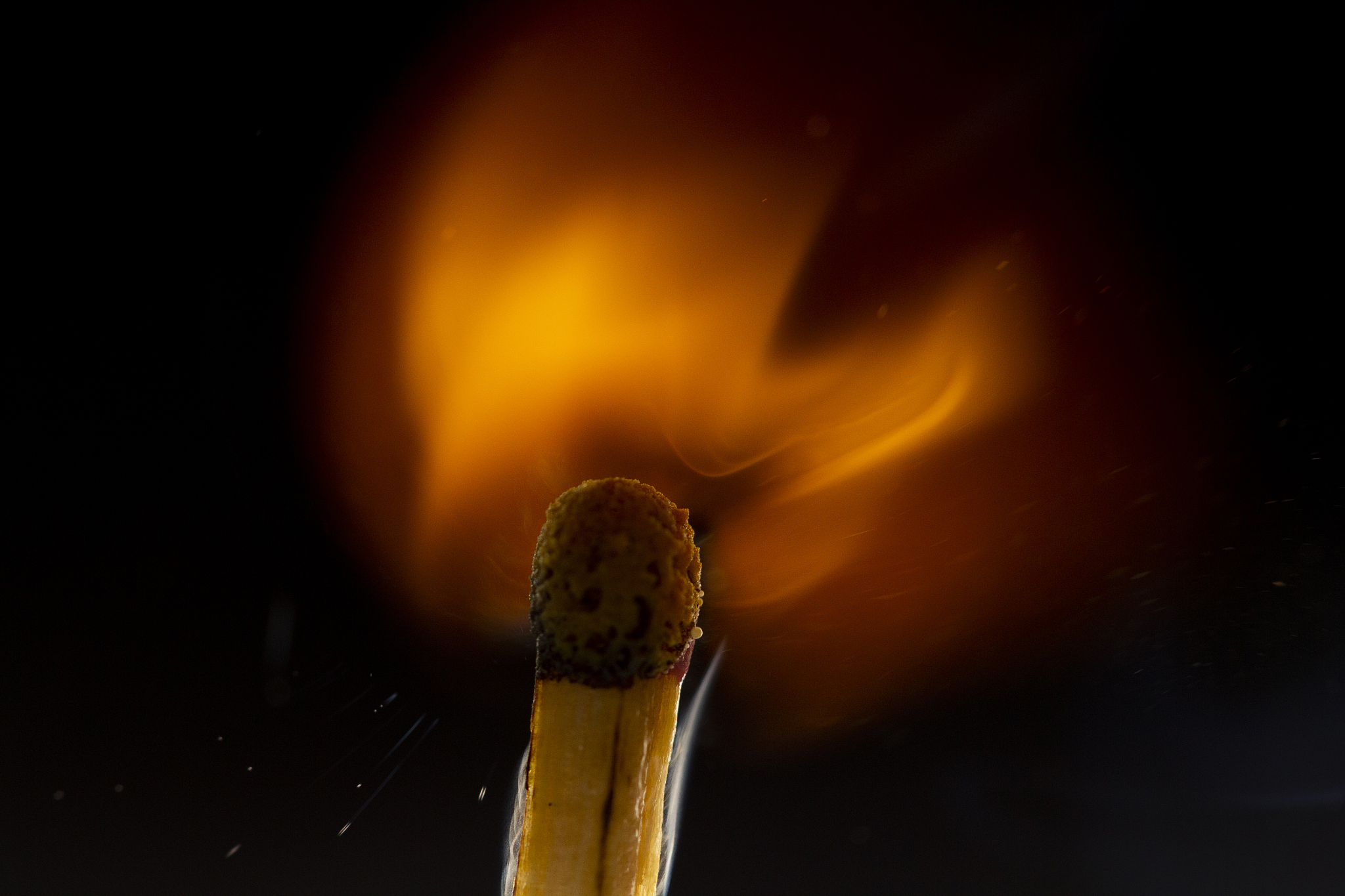 burning wooden match with a red match head on a black background