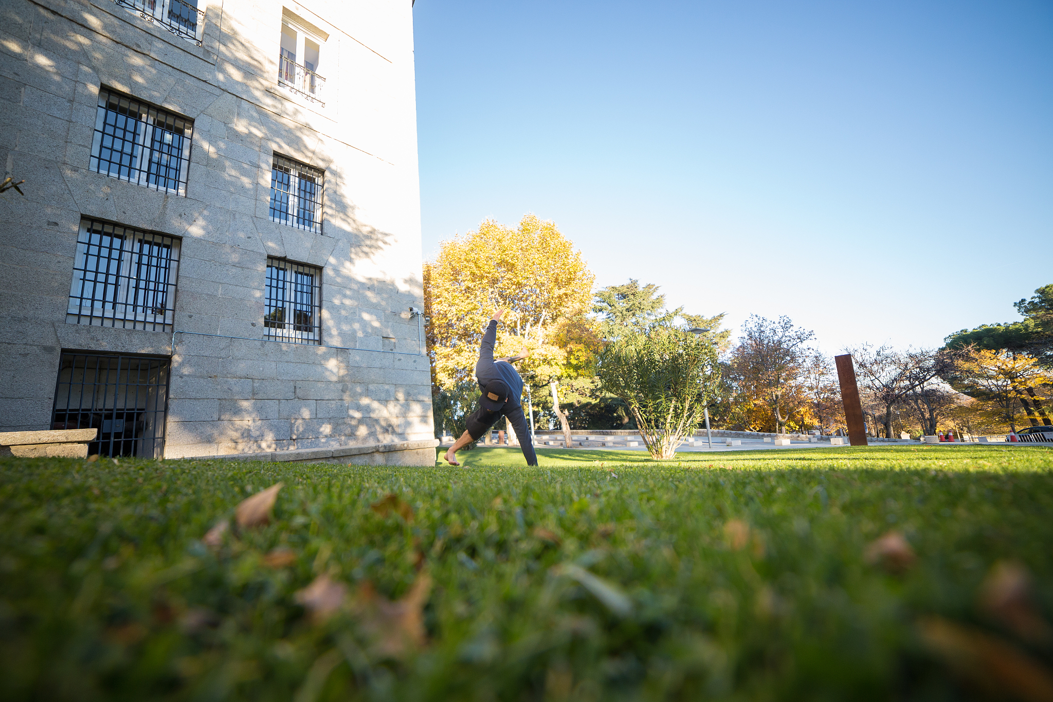 low angle view of man jumping on field by building
