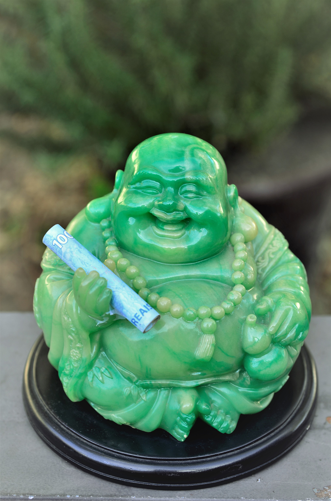 a friendly green buddha with money in hand