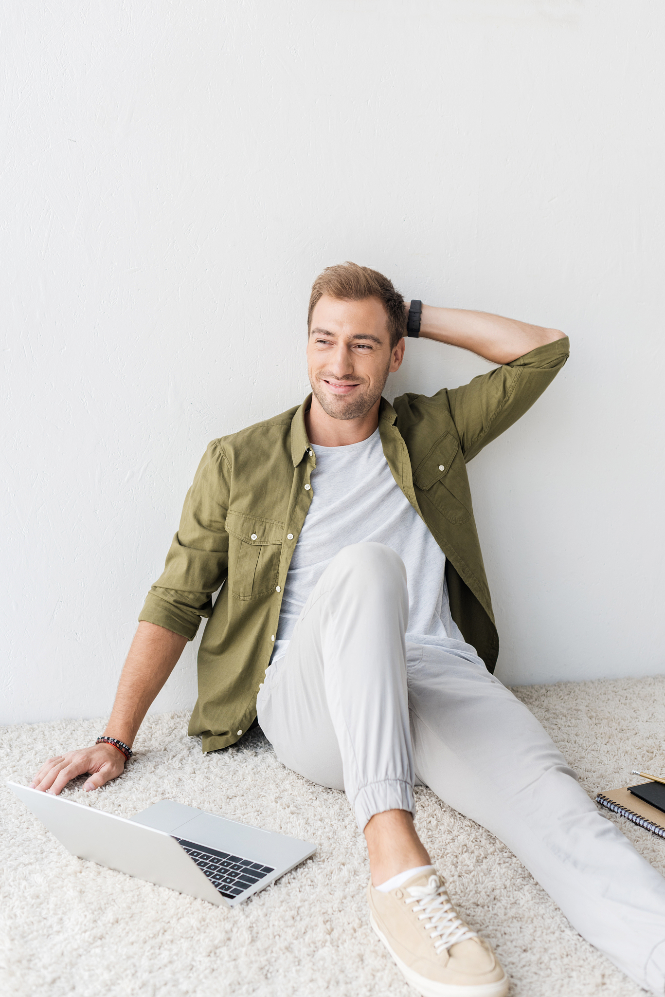 smiling man sitting on beige rug and looking away