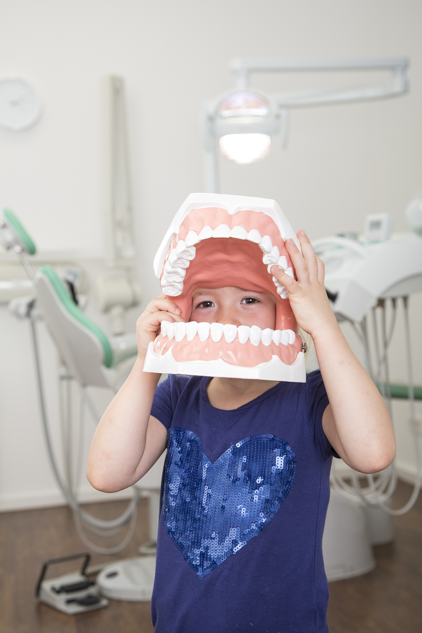 girl in dental sugery holding big tooth model