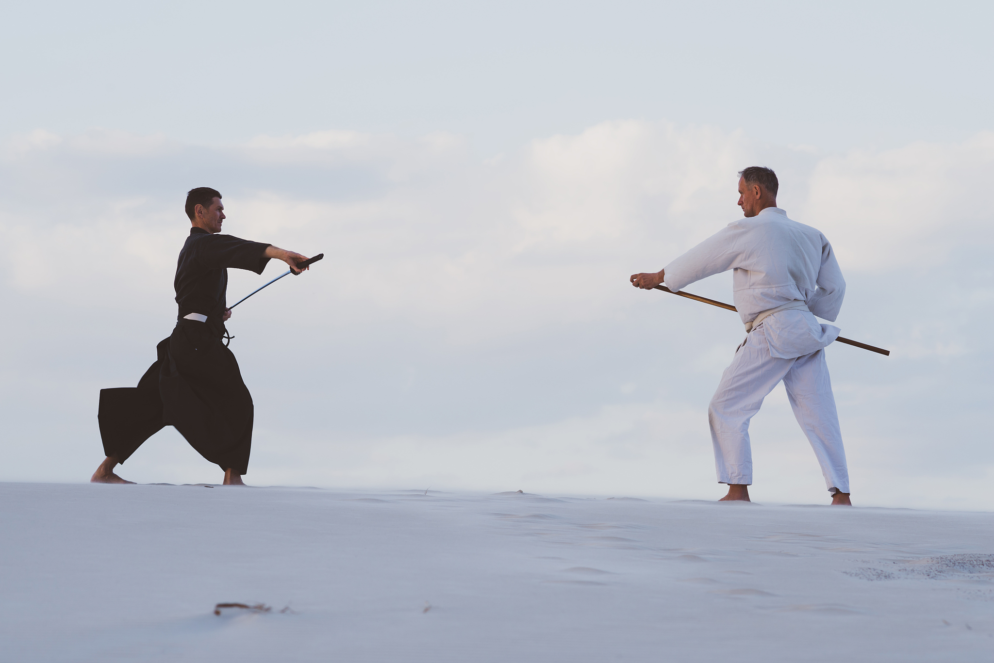 two men practicing japanese martial arts in desert