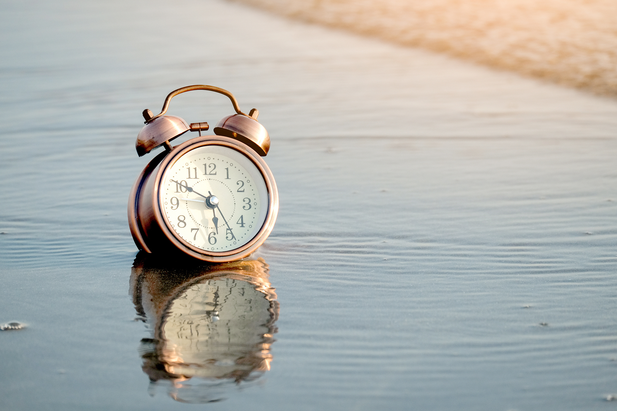 alarm clock on beach background water sea