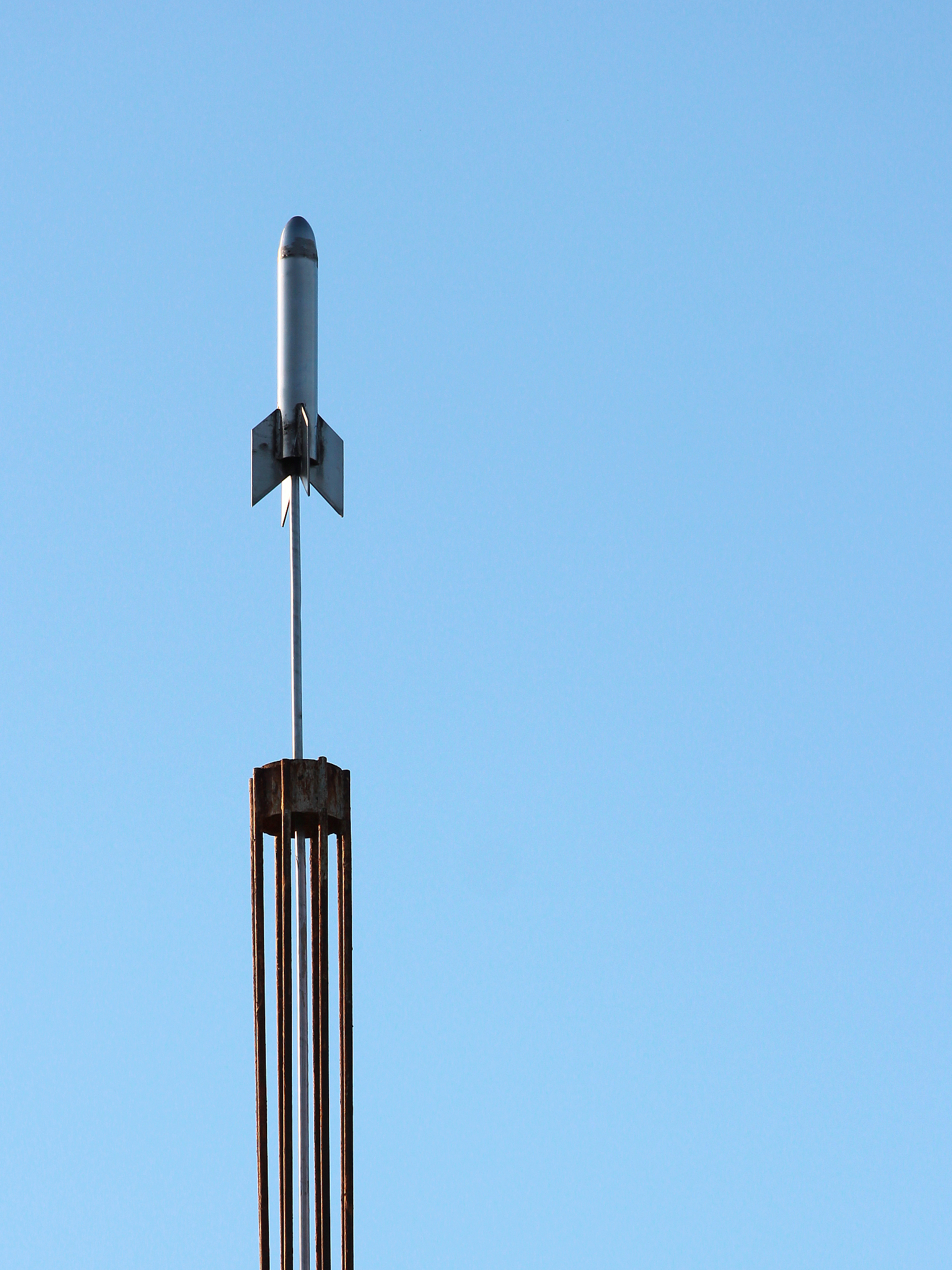 stylized abstract metal rocket against blue sky background