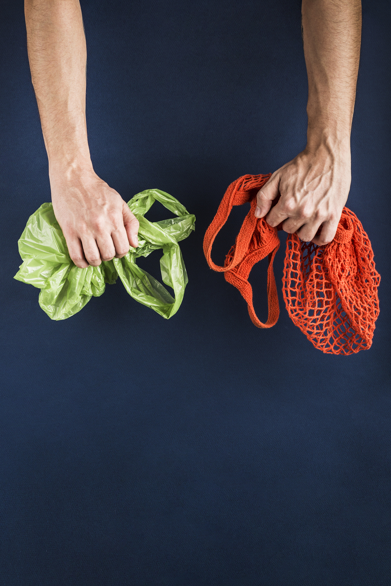 a string bag in one man's hand, in the other a plastic bag on a 