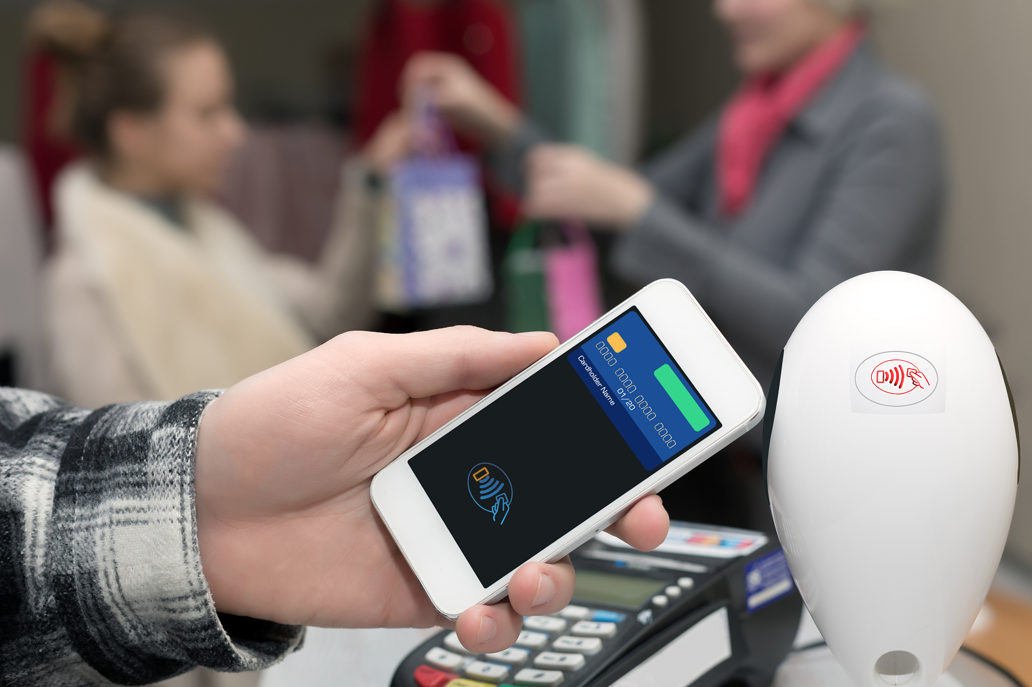 man completing mobile payment at store cashiers desk with termin