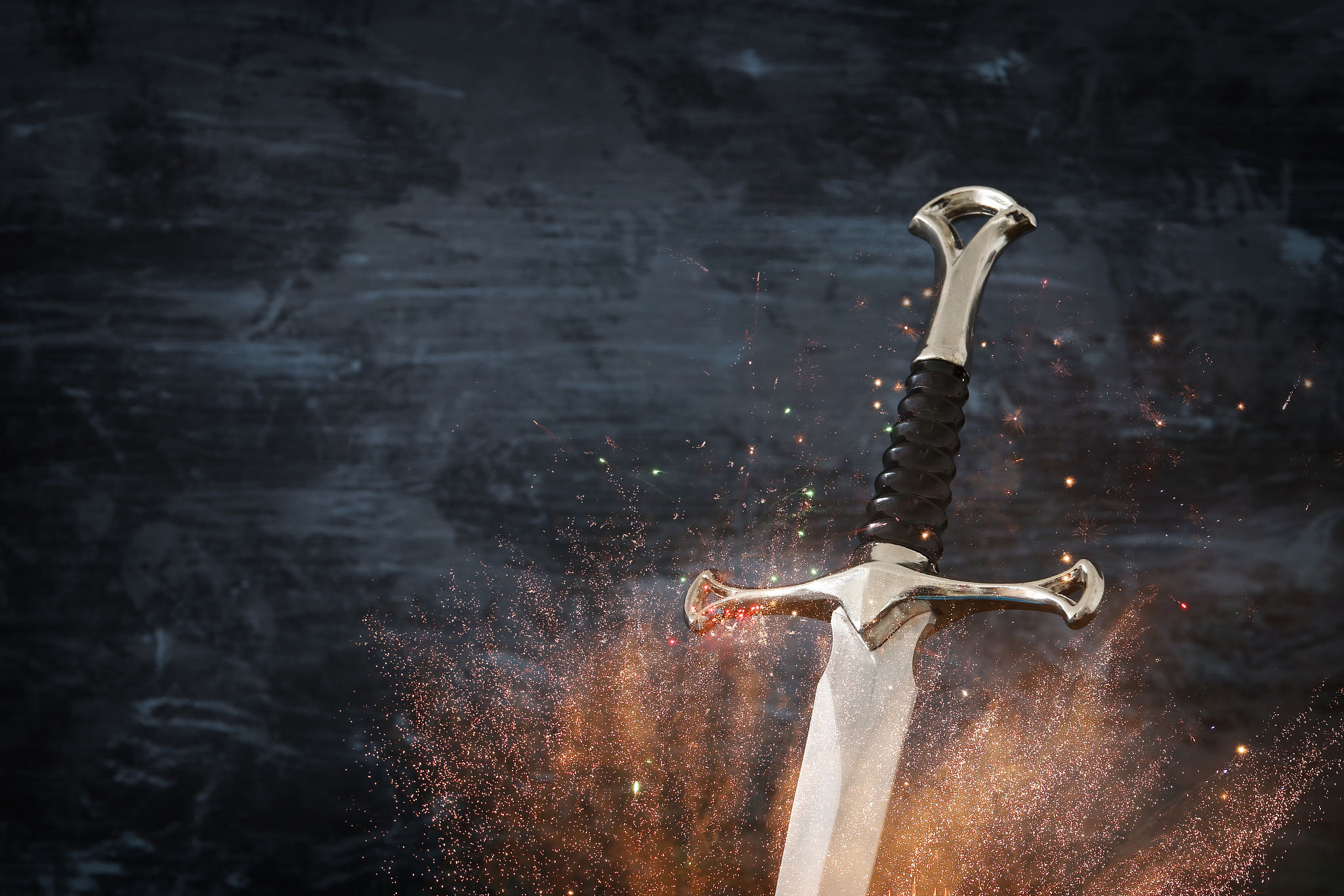 low key image of silver sword with fire sparks. fantasy medieval