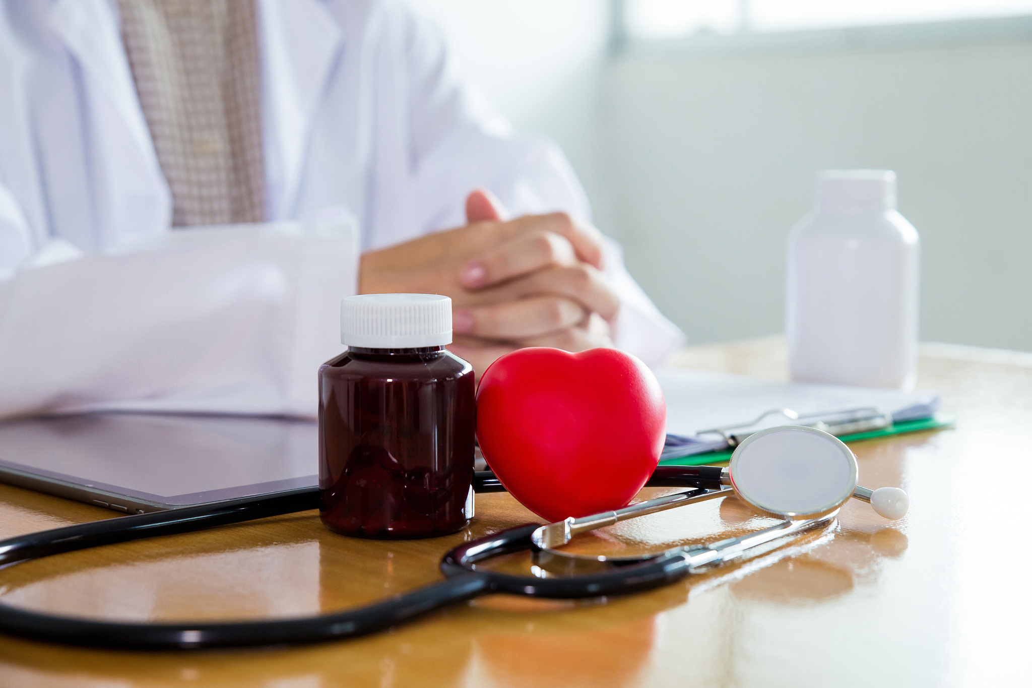 bottle of medicine,red heart ball, black stethoscope are put on 