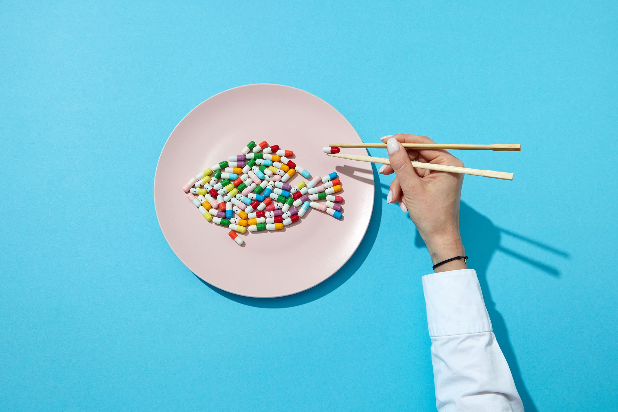 fish from colorful pills and tablets on a white plate and woman'