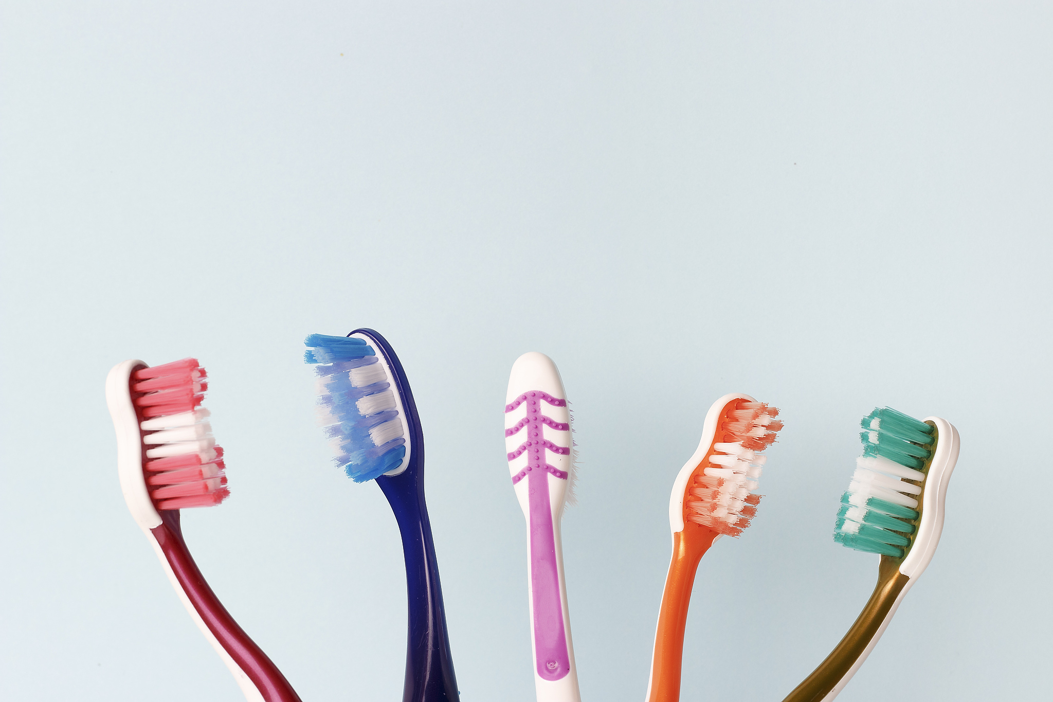 multicolored toothbrushes on a blue background, copy space