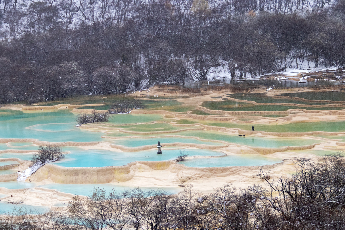 四川黄龙国家公园的雪山盆地中,绿松石色的层叠石灰华