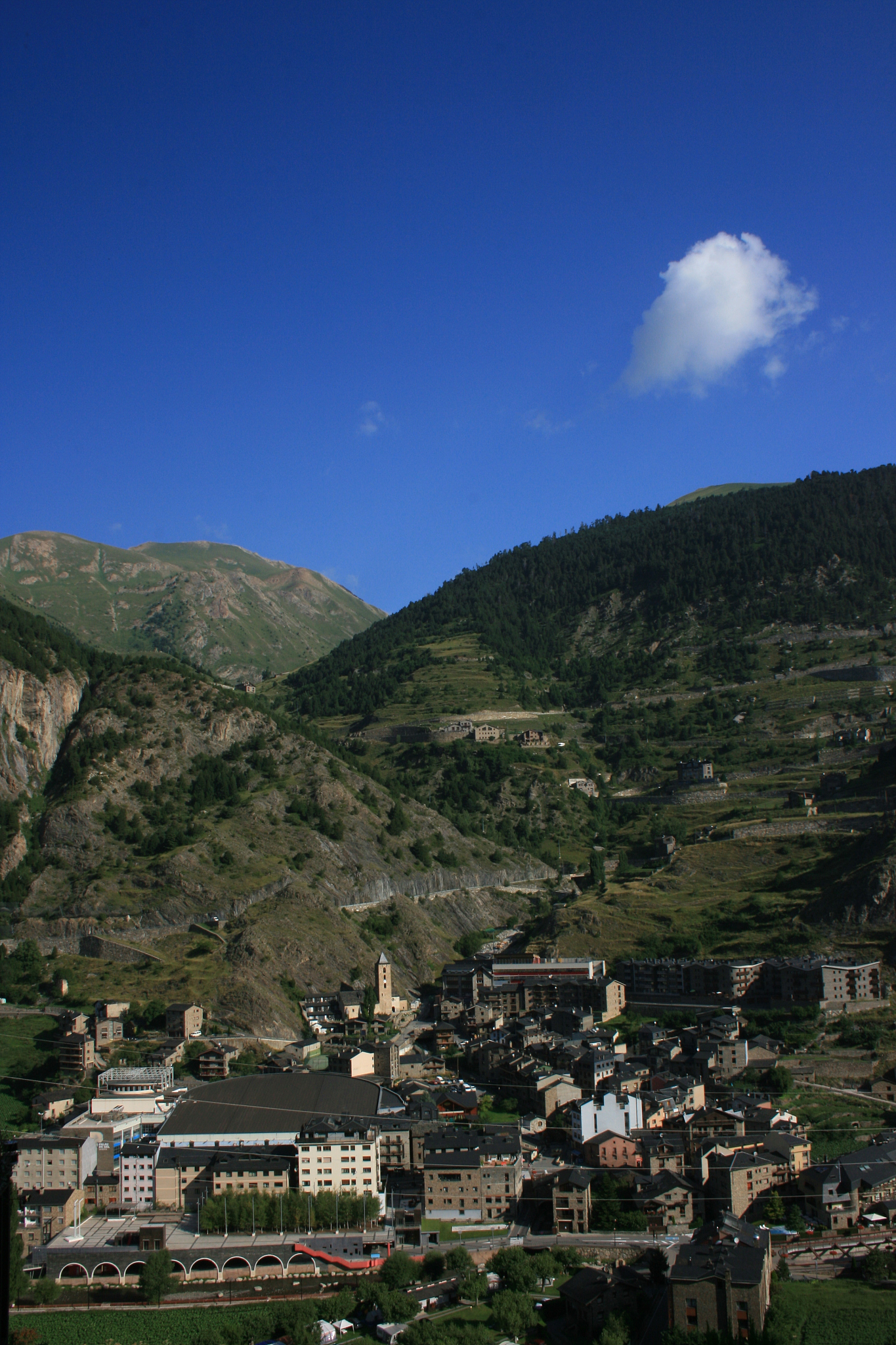 scenic view of townscape by mountains against blue sky