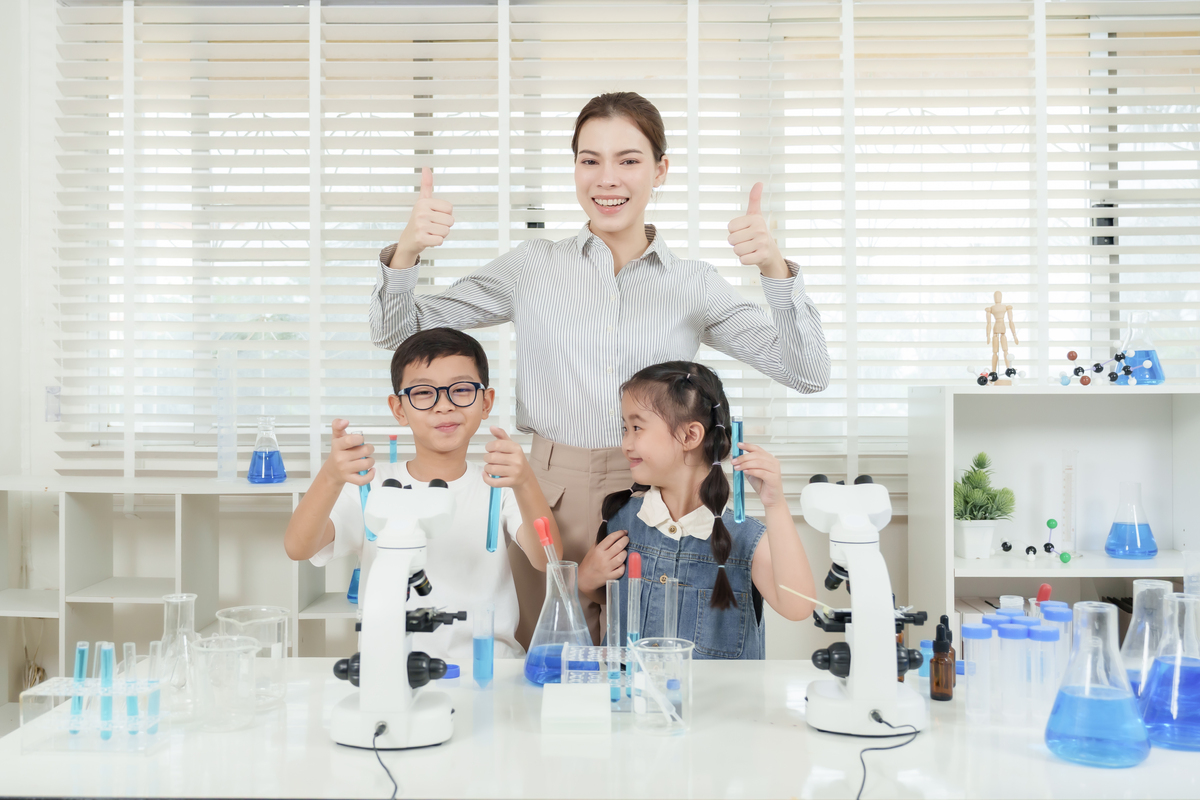 一群亚洲学生和一位白人女老师在小学<strong>科学</strong>课上,在摆满