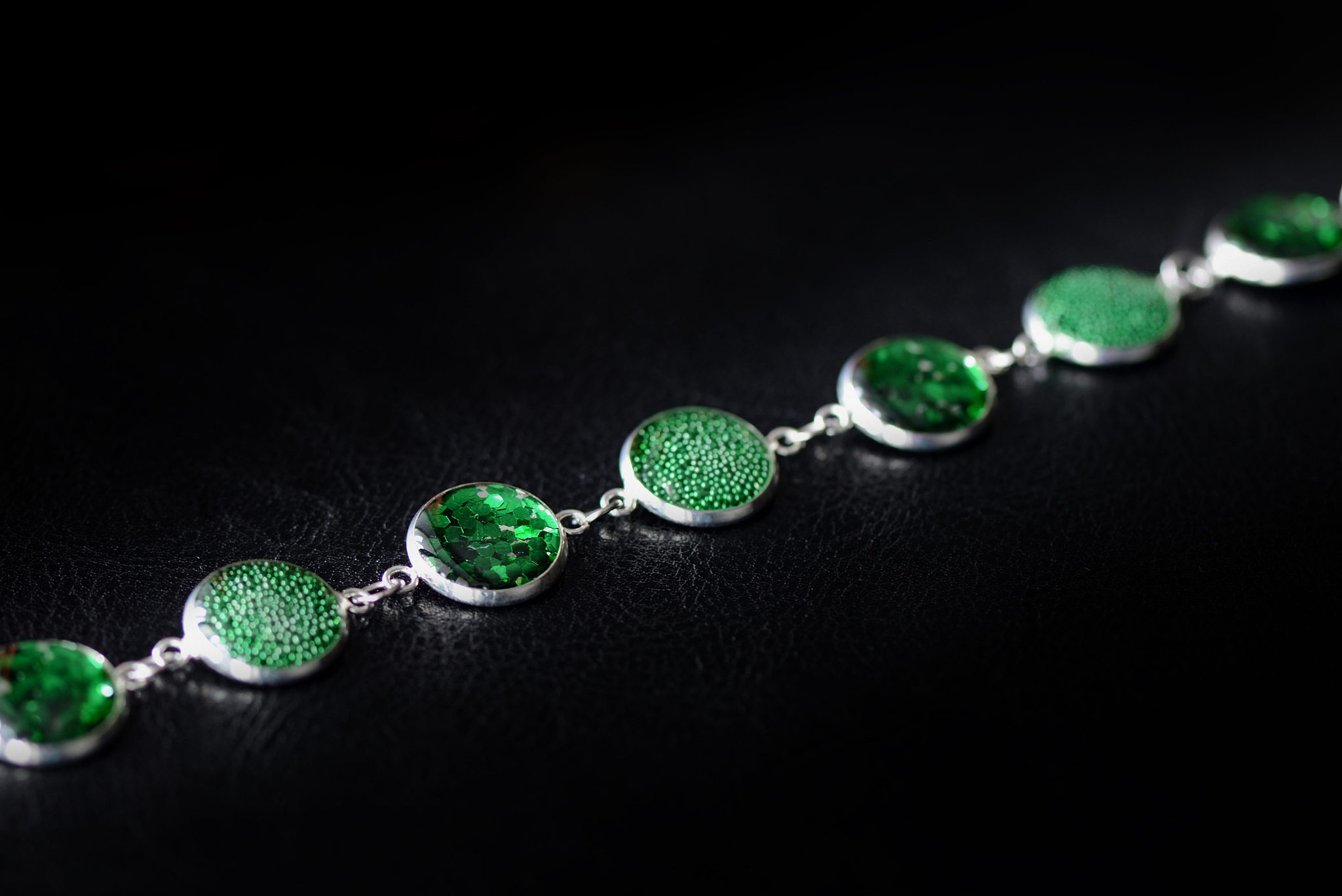 resin bracelet with green sparkles on a dark background close up