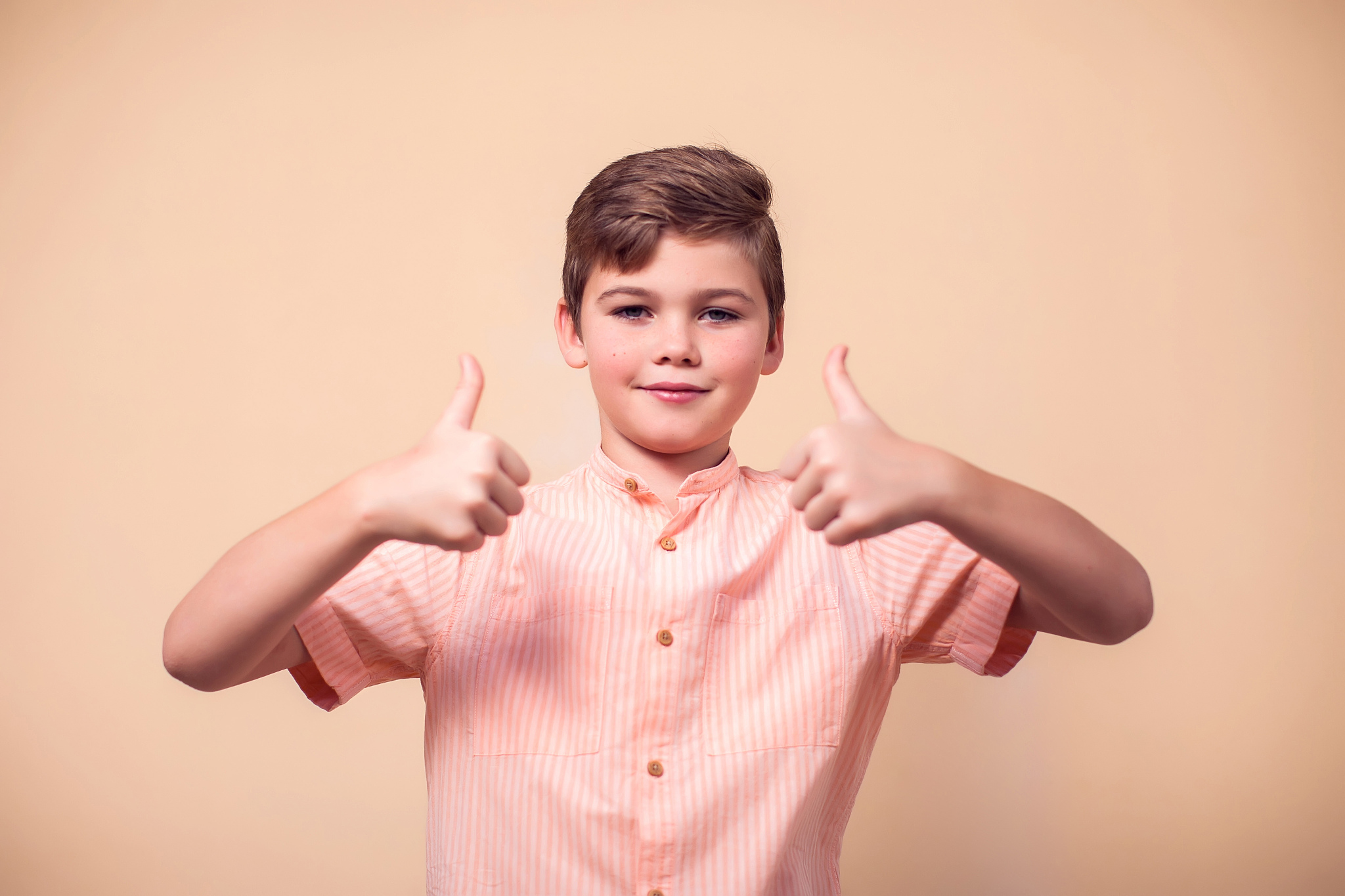 a portrait of kid boy showing thumb up gesture. children and emo