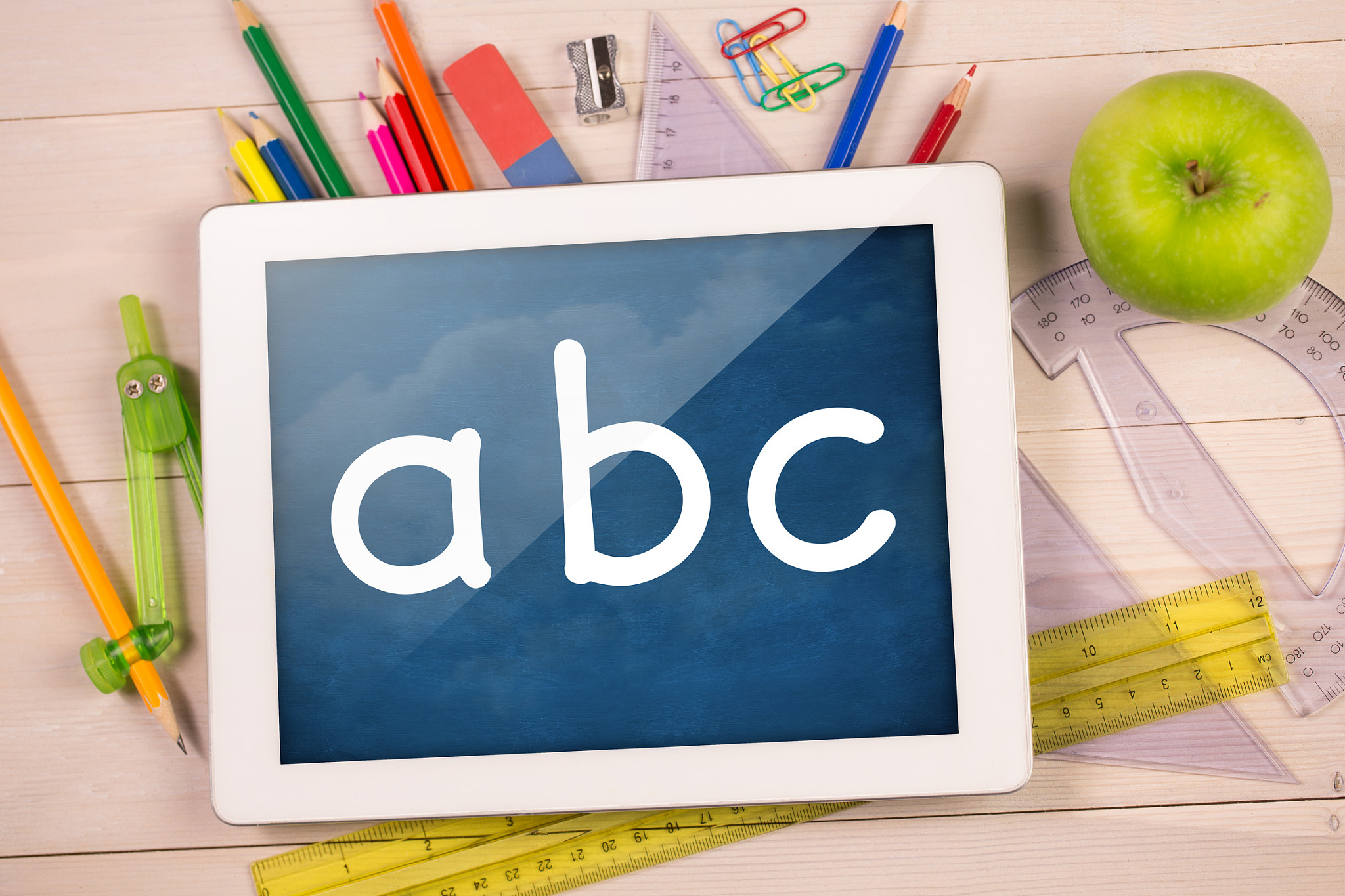 composite image of digital tablet on students desk showing abc