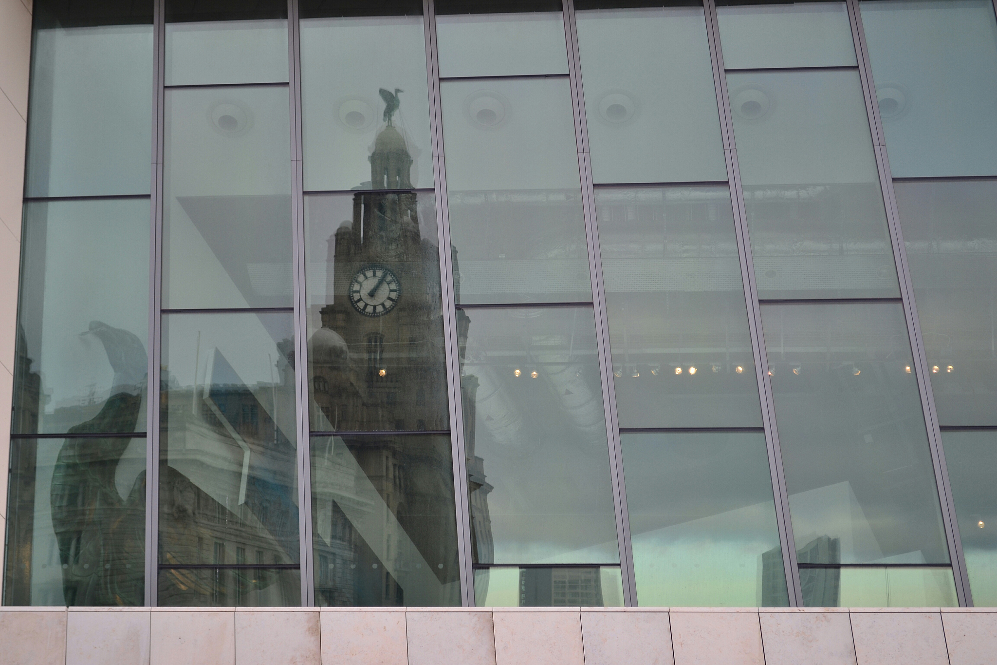 low angle view of clock tower reflection on glass building