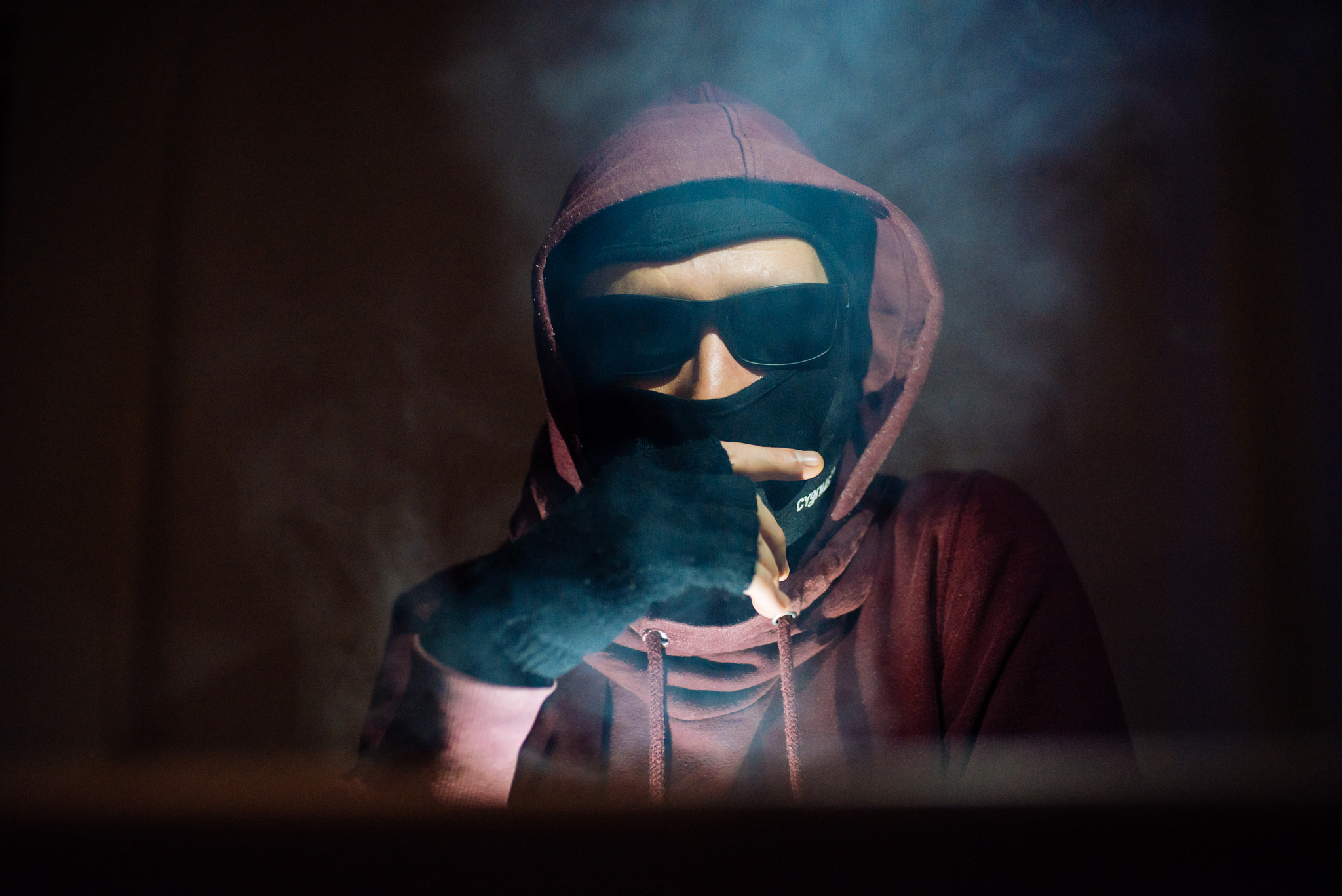 portrait of a hacker in hoodie in dark room