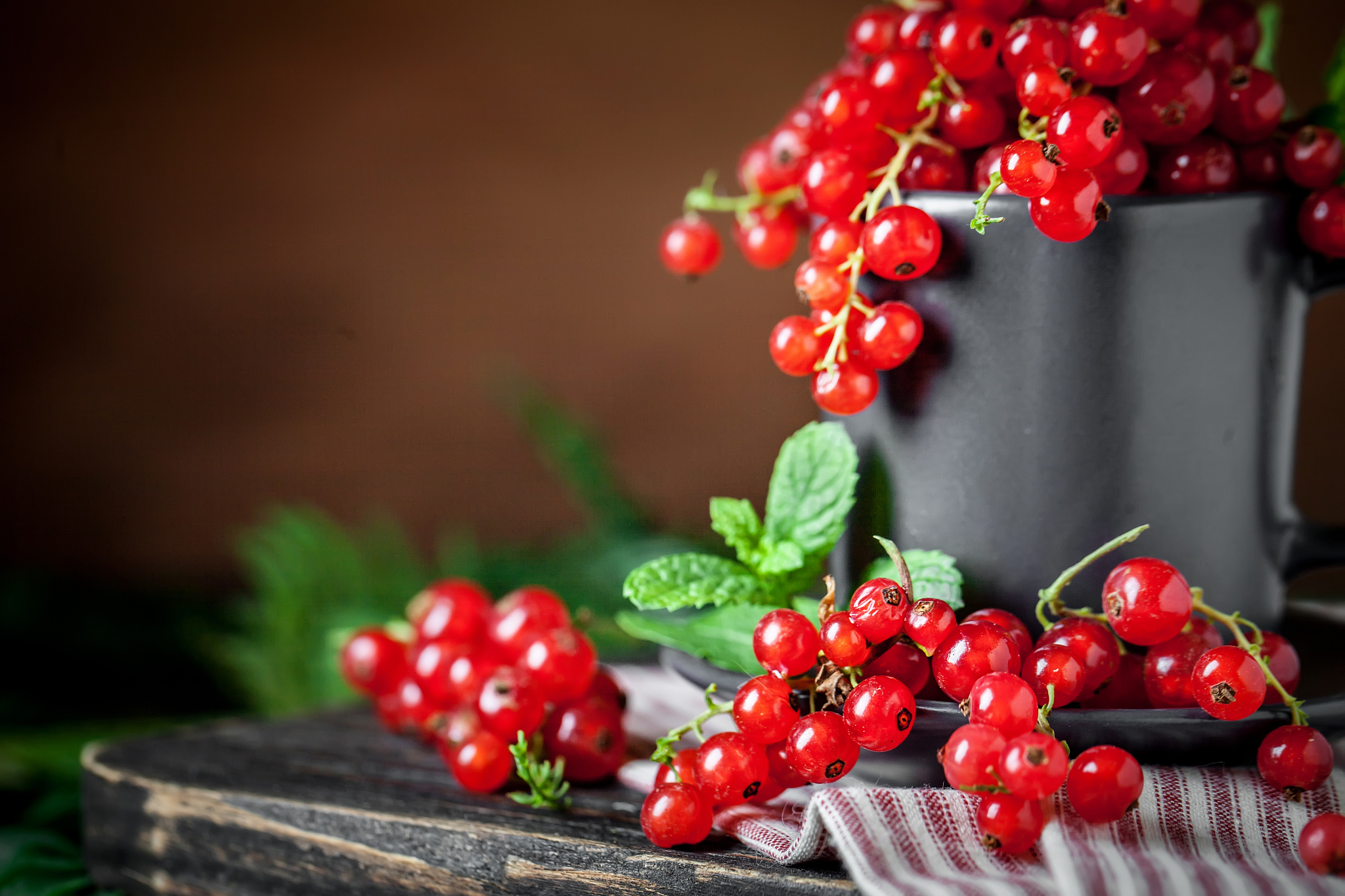 fresh red currants in a cup on a dark rustic wooden table. backg