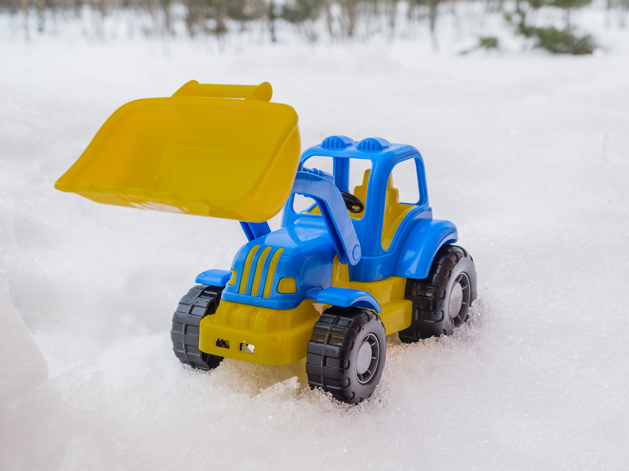 toy tractor with front loader in the snow. concept of utilities 