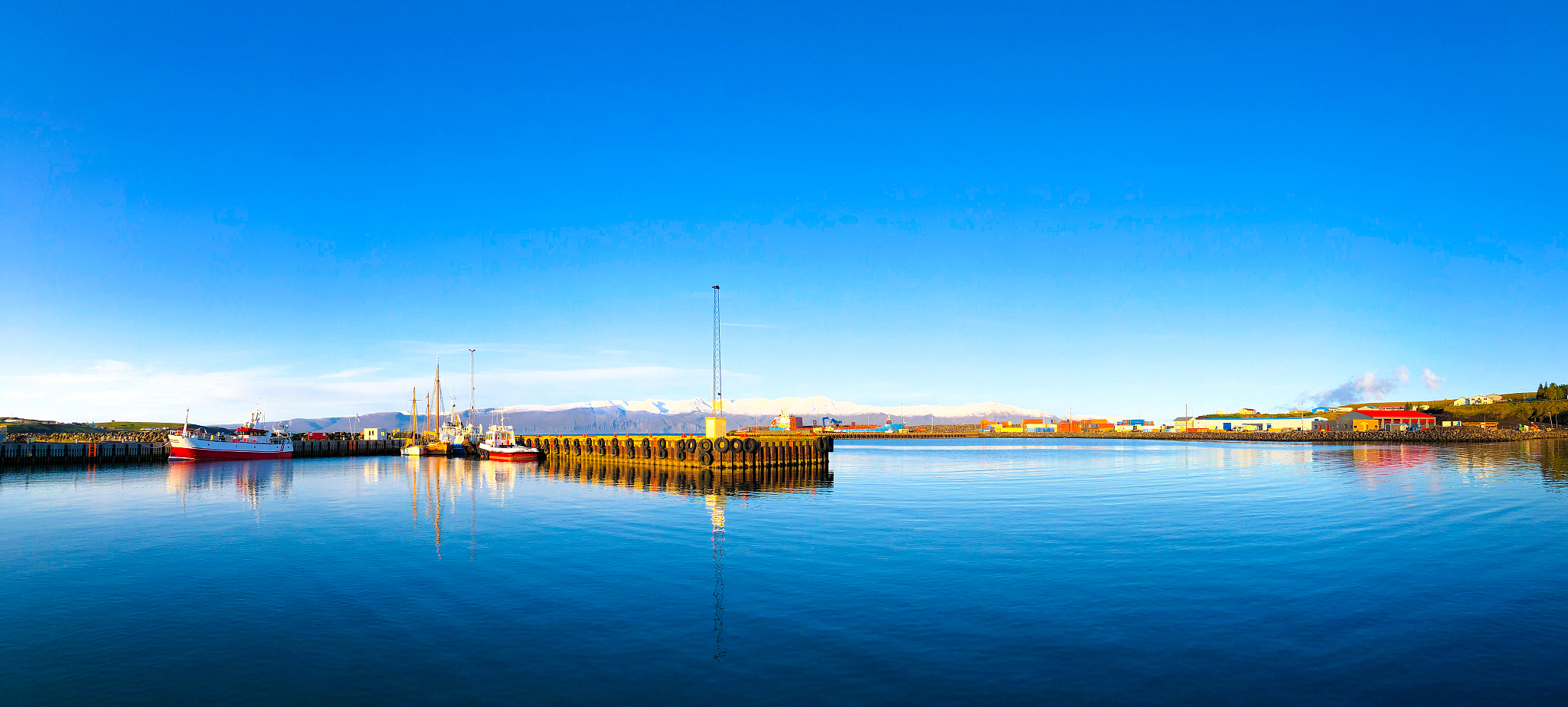 húsavík, iceland: ships in sunlit harbor in early morning pano