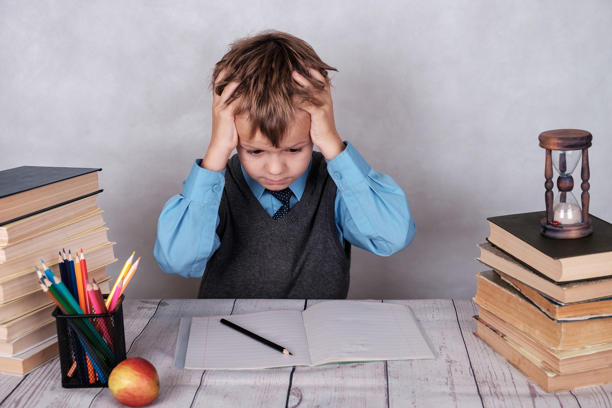tired of the lessons of the european boy at the table with books