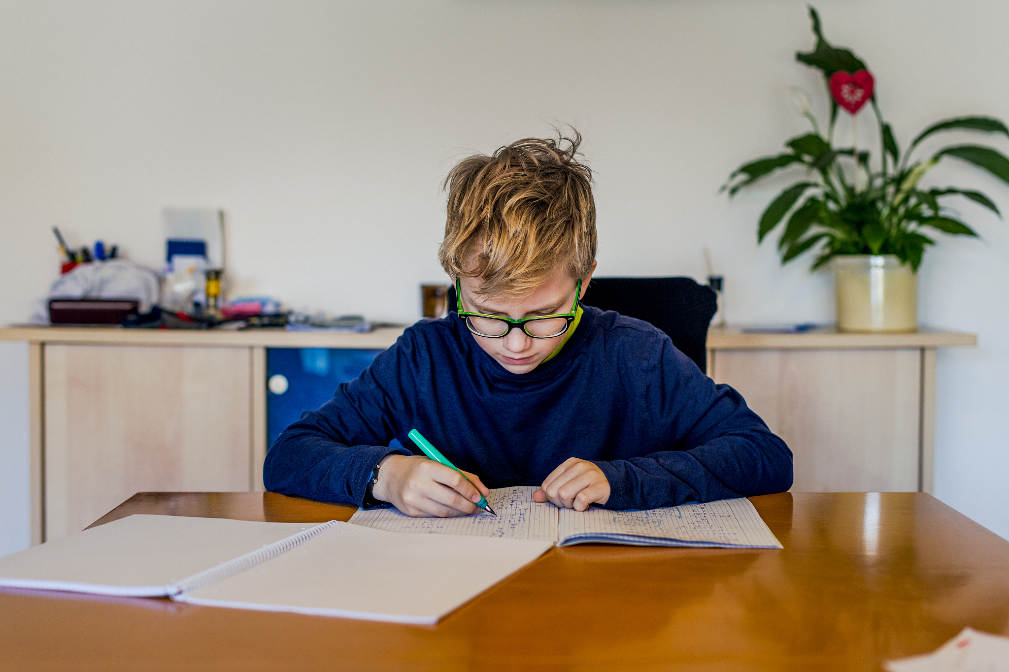 teenager doing homework at dining table