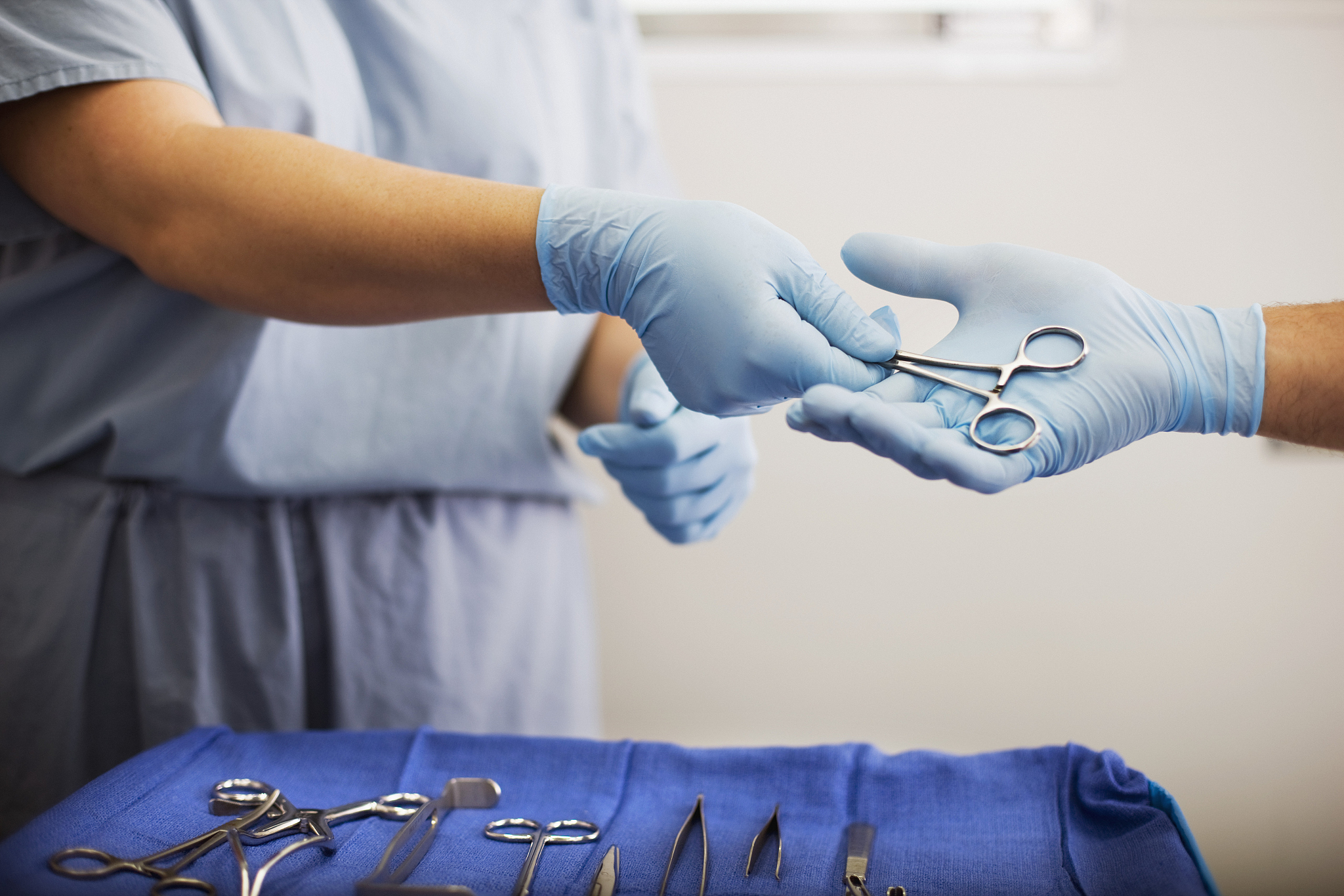 assistant passing surgical tools to surgeon