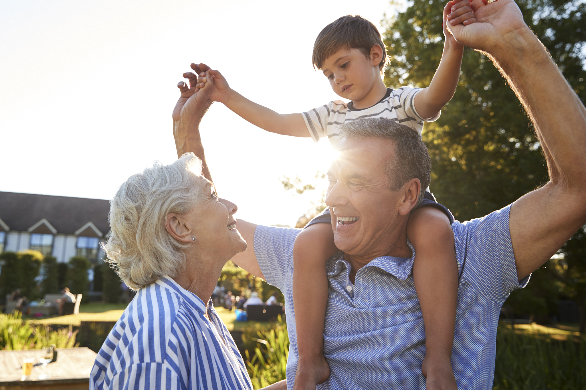 grandparents giving grandson ride on shoulders in summer park ag