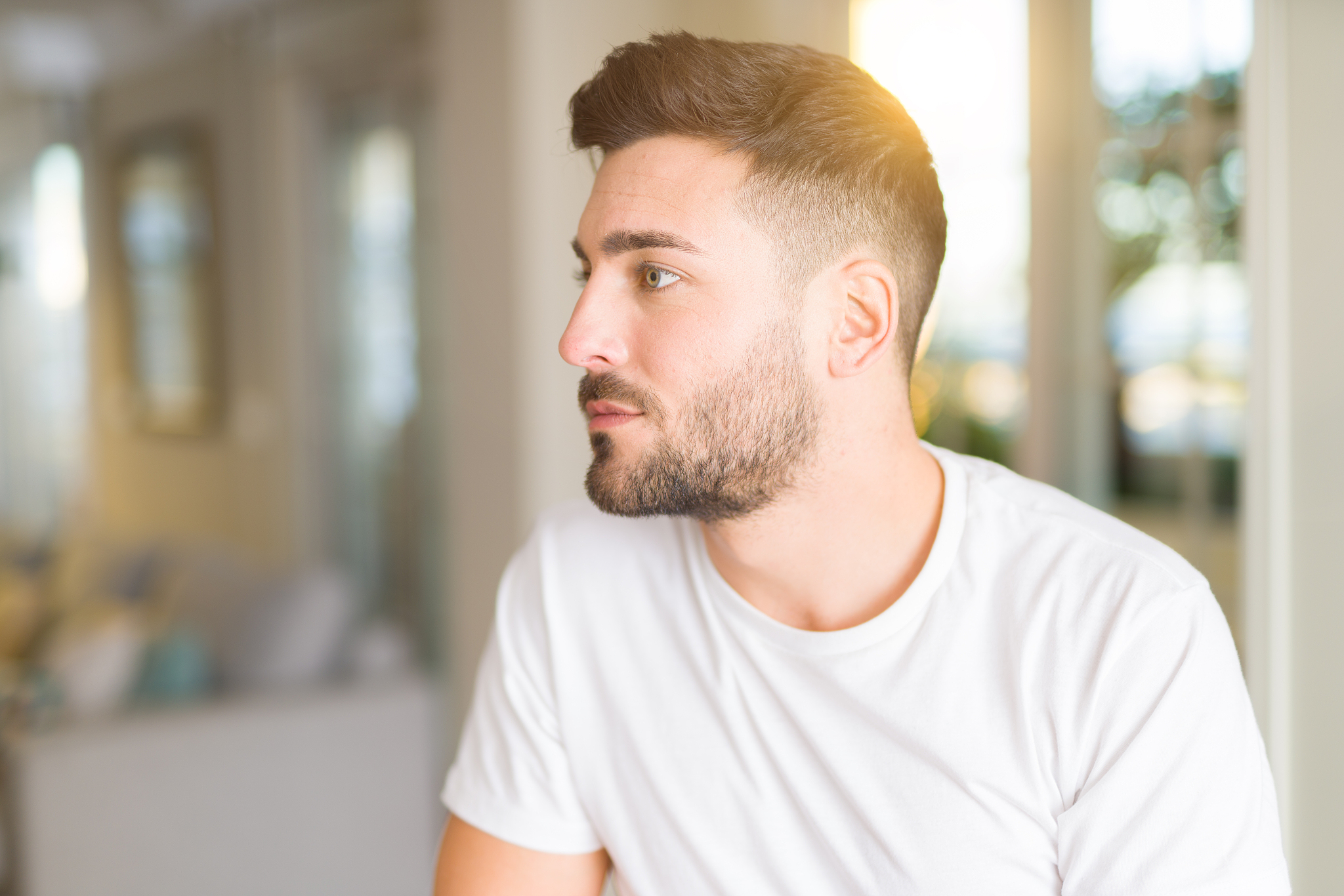 young handsome man wearing casual white t-shirt at home looking 
