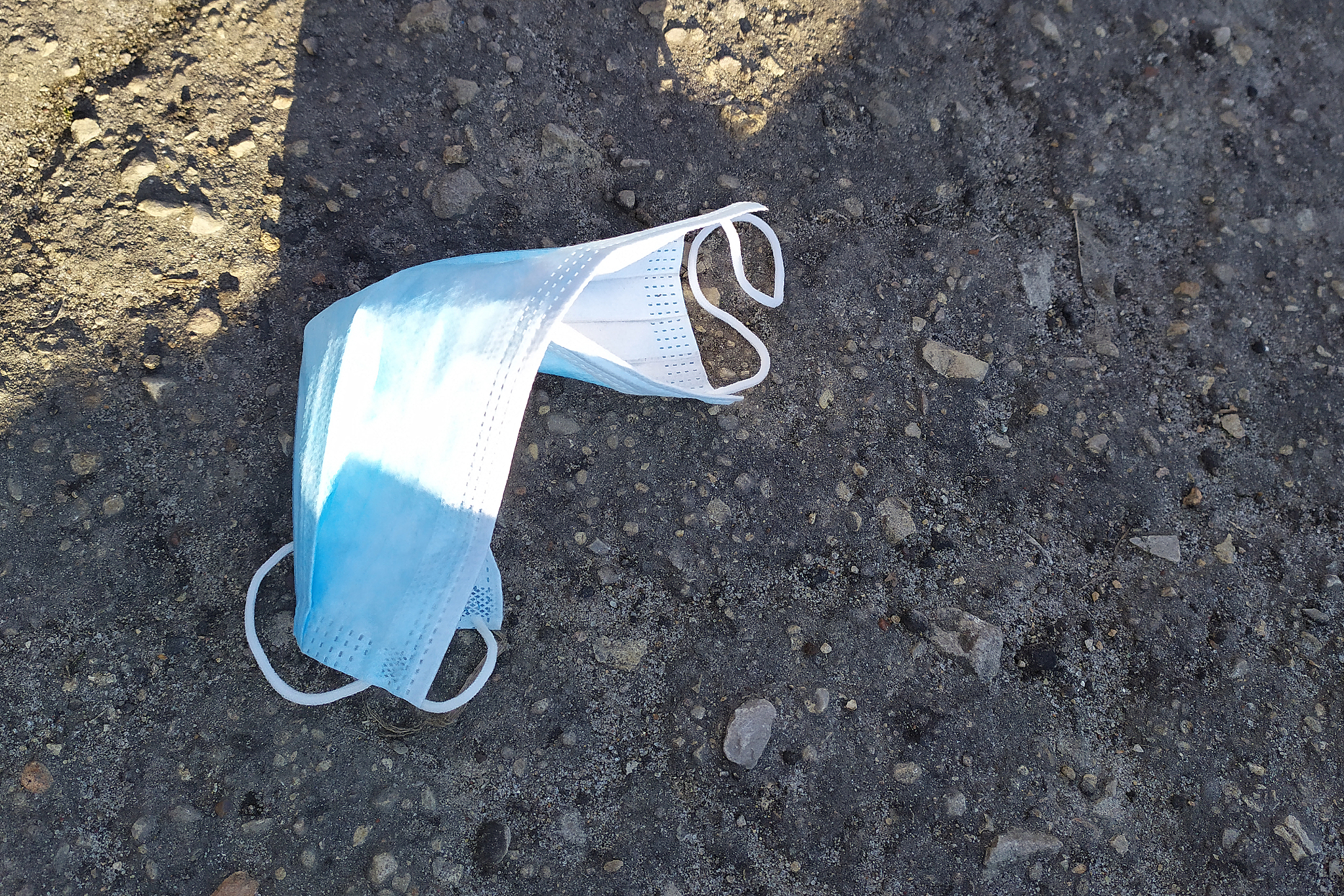 blue medical mask on pavement, end of quarantine, epidemic of co