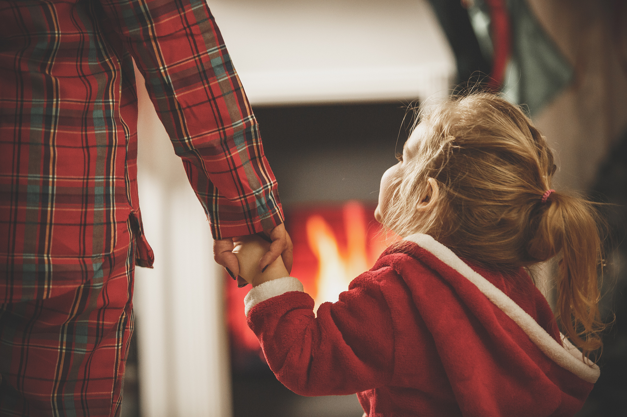 woman and little girl holding hands by the fireplace