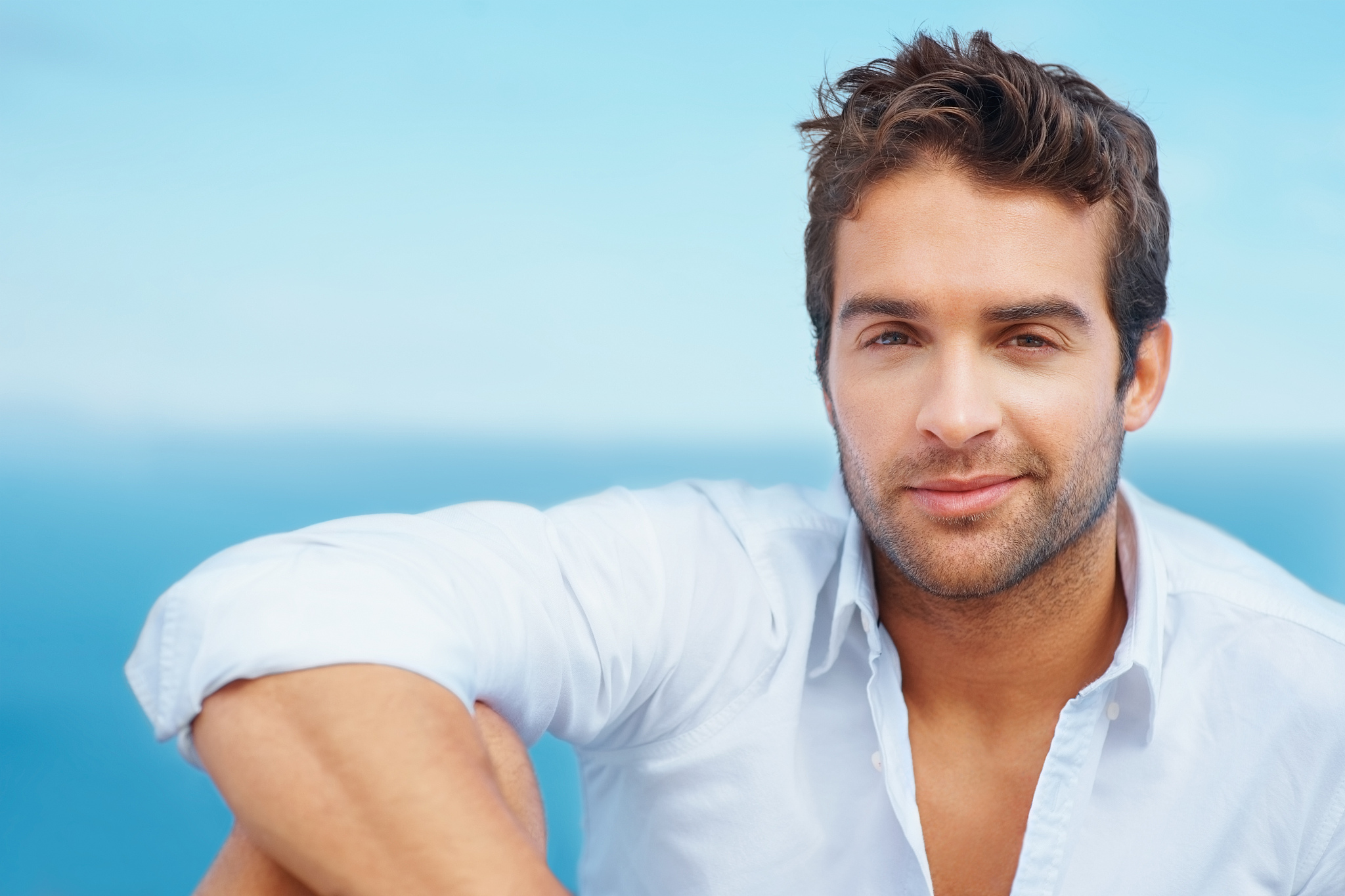 smart young guy smiling against the blue sky