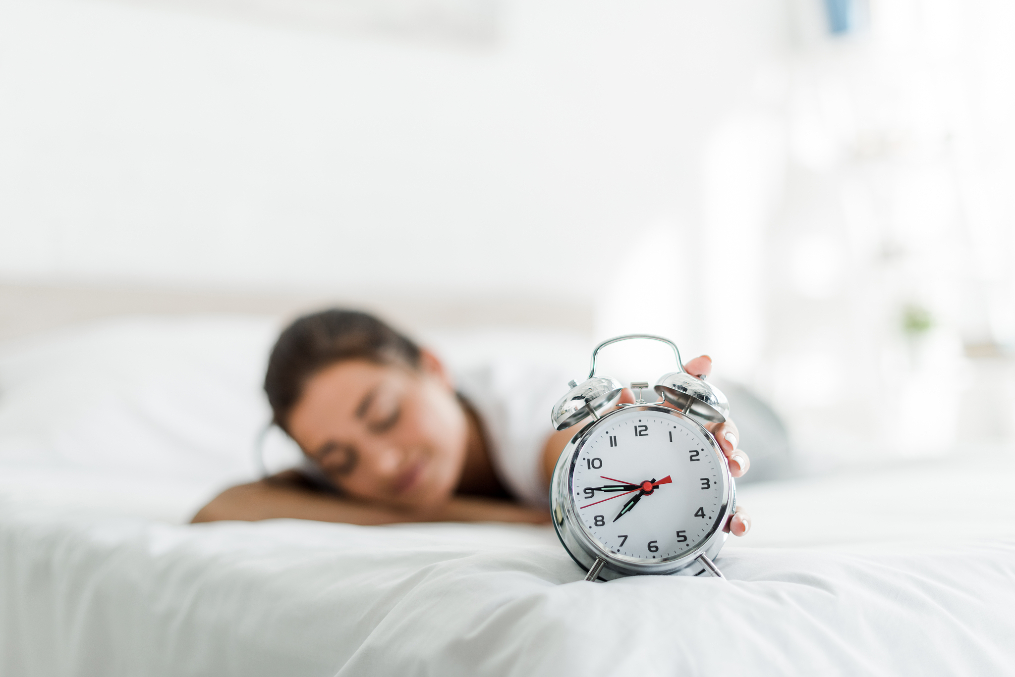 selective focus of sleeping woman with alarm clock on bed  in th