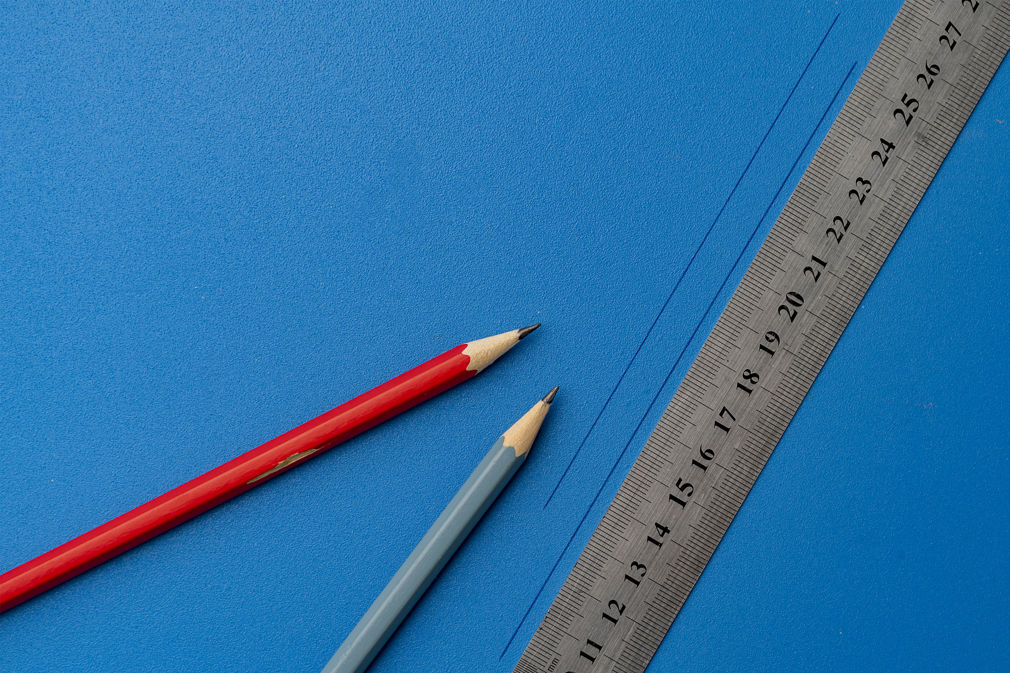 drawing a line on a color surface with a ruler and pencil