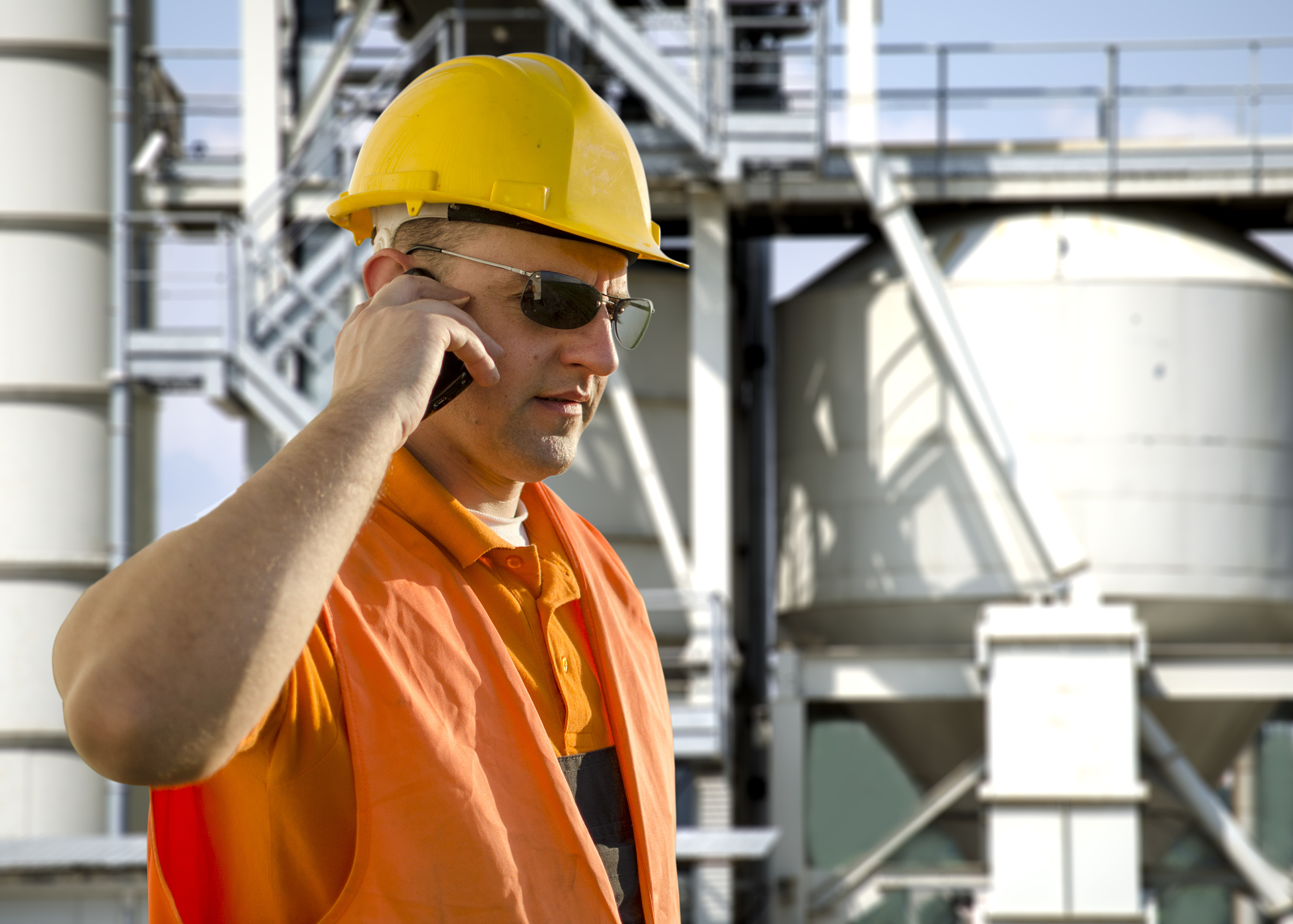 worker with helmet and sunglasses talking on mobile phone