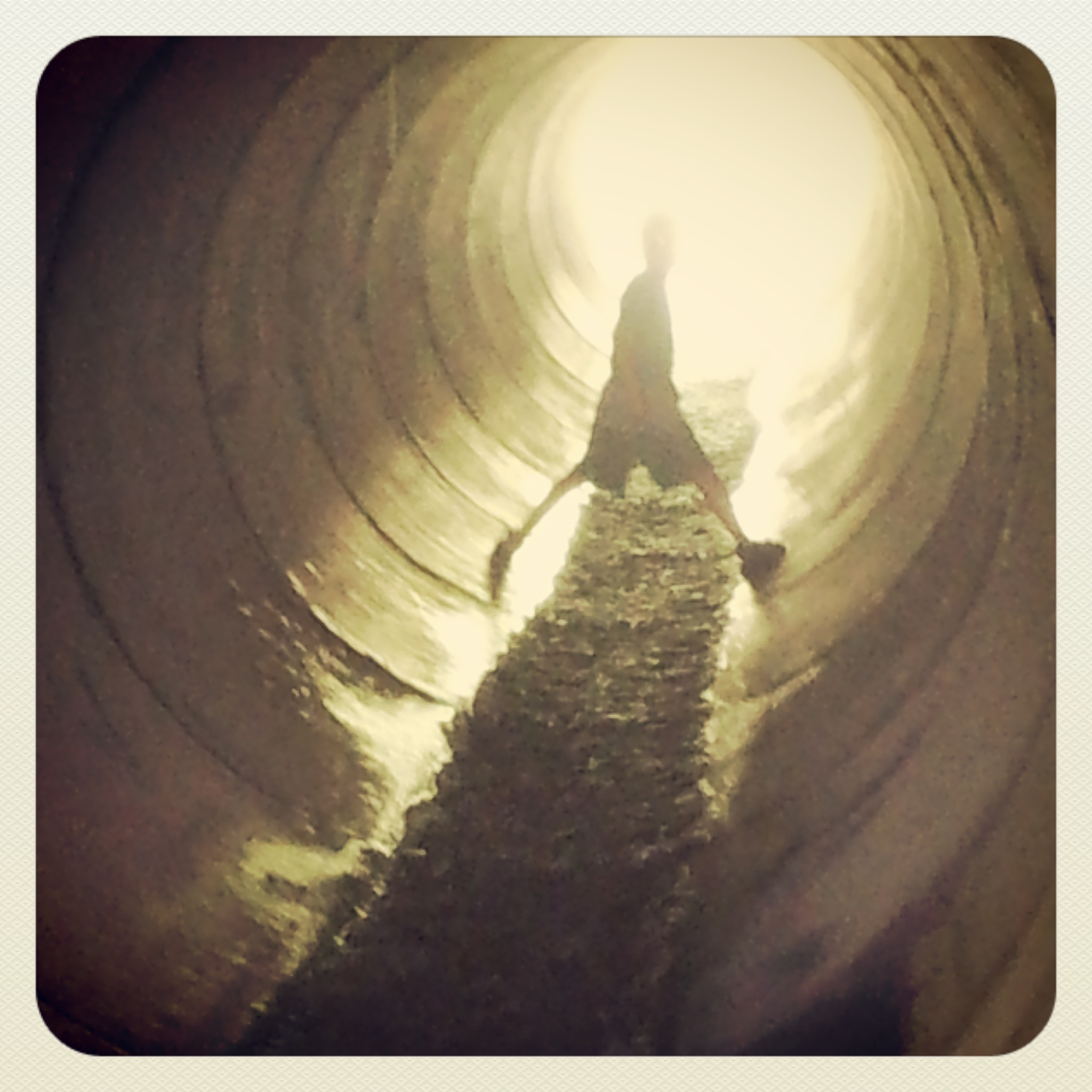 boy standing in tunnel against light
