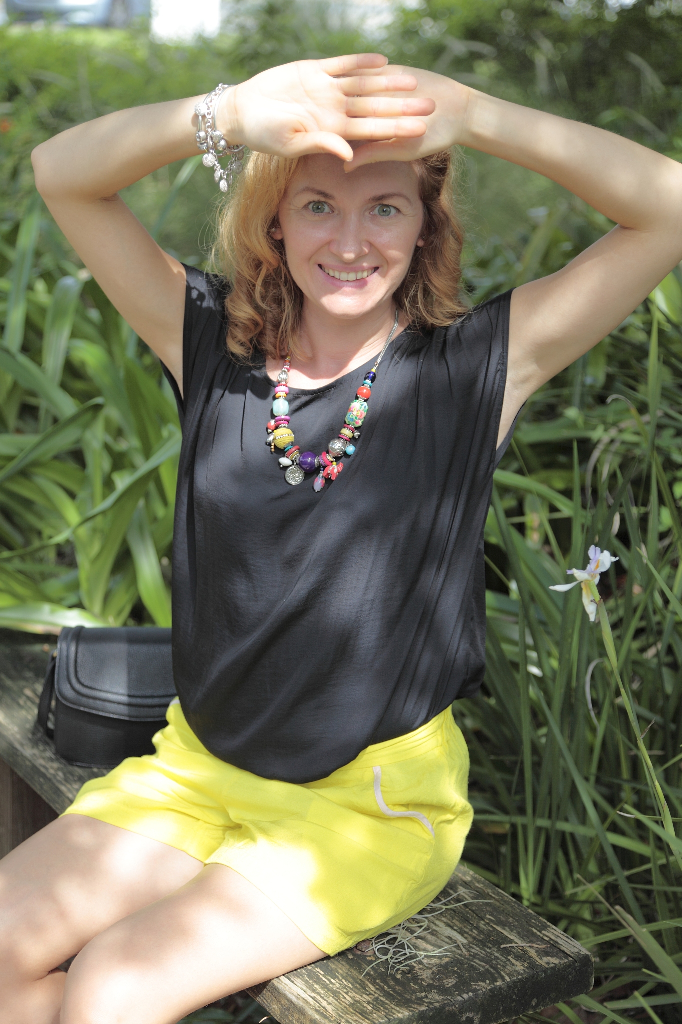 young woman is sitting on a bench in a park.