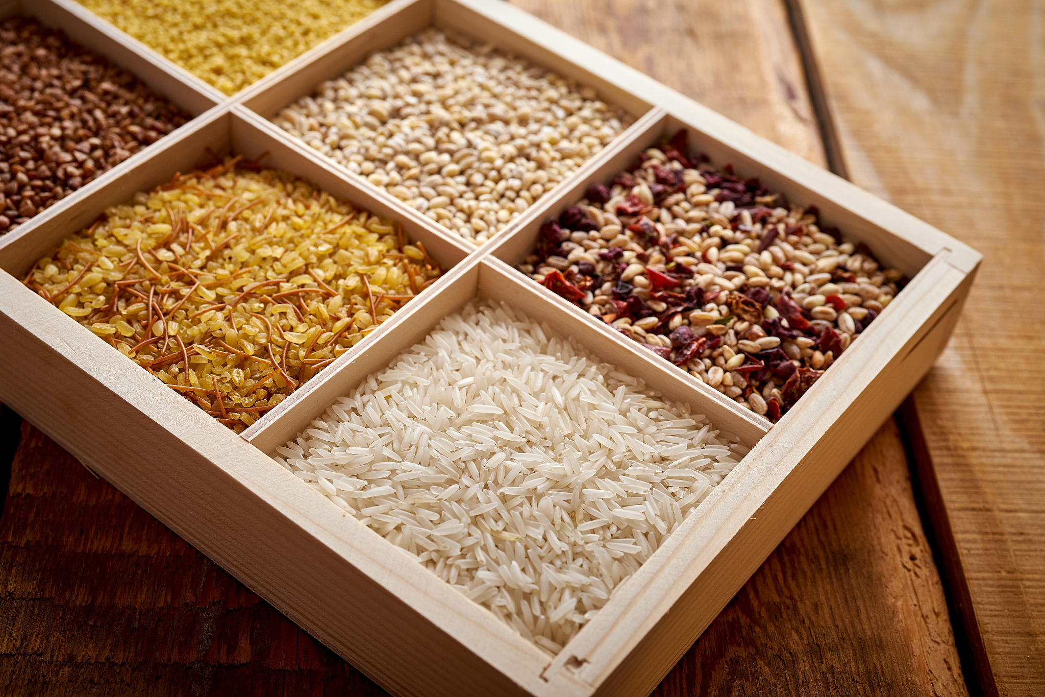different, colorful types of groats in a wooden box