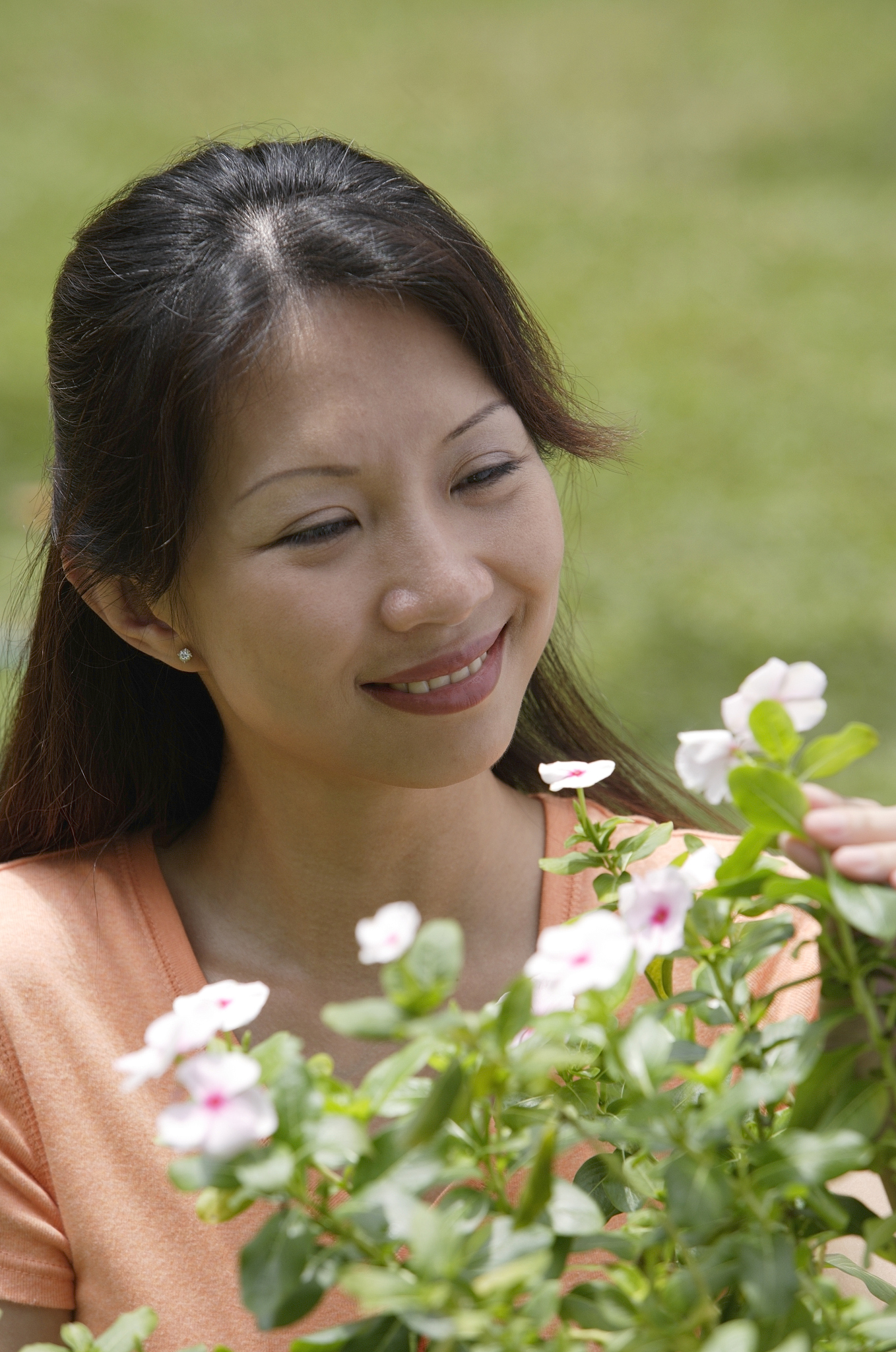 woman outdoors, looking at flowering plants