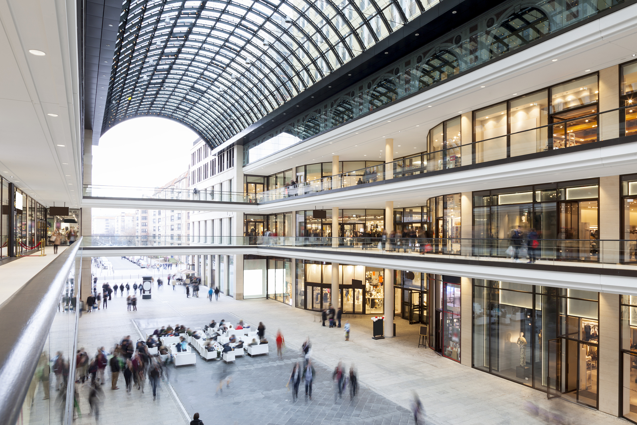 modern shopping mall with stores, cafe and shoppers walking arou