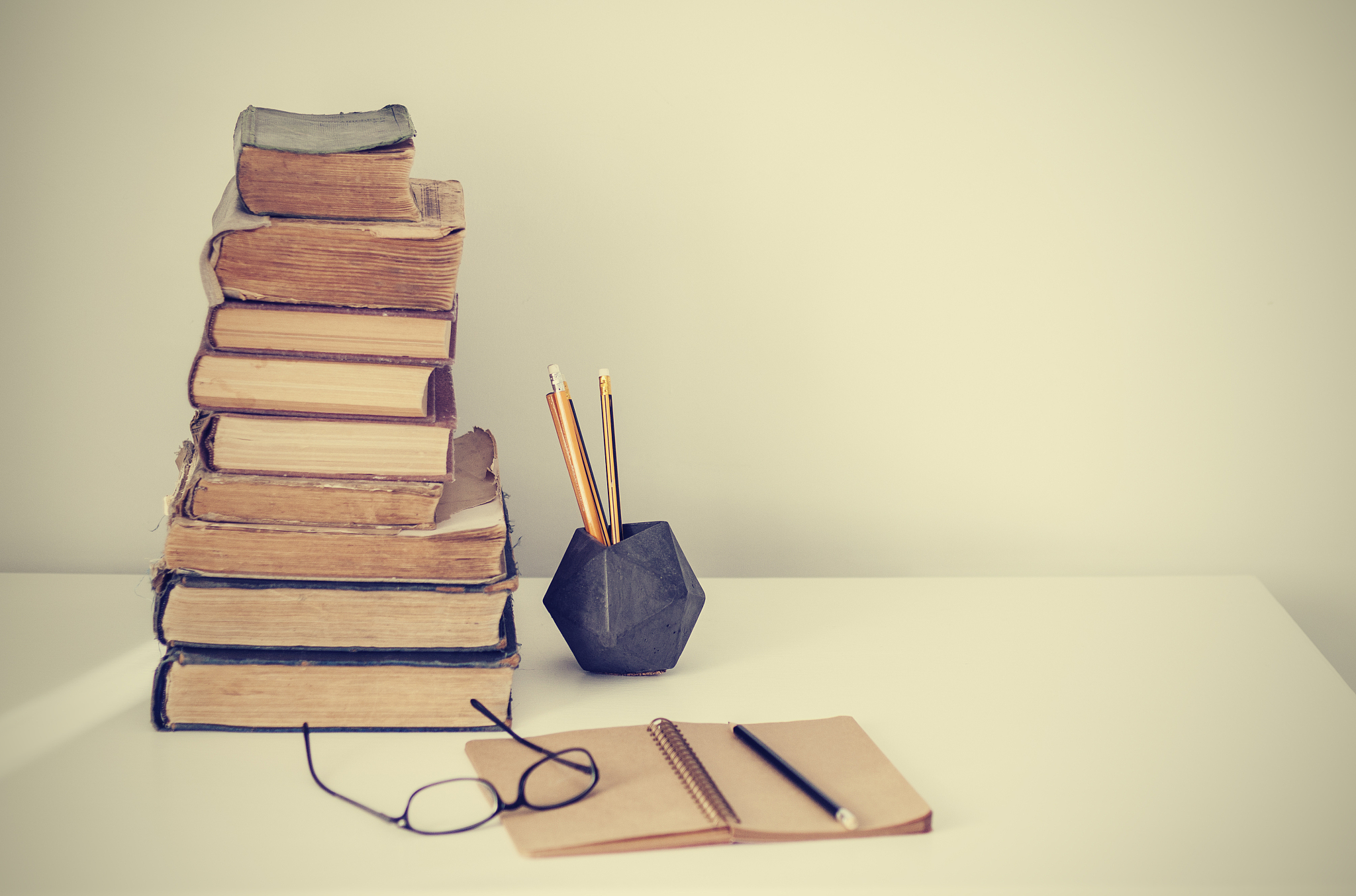 stack of old books, textbook, glasses and pencils in office back