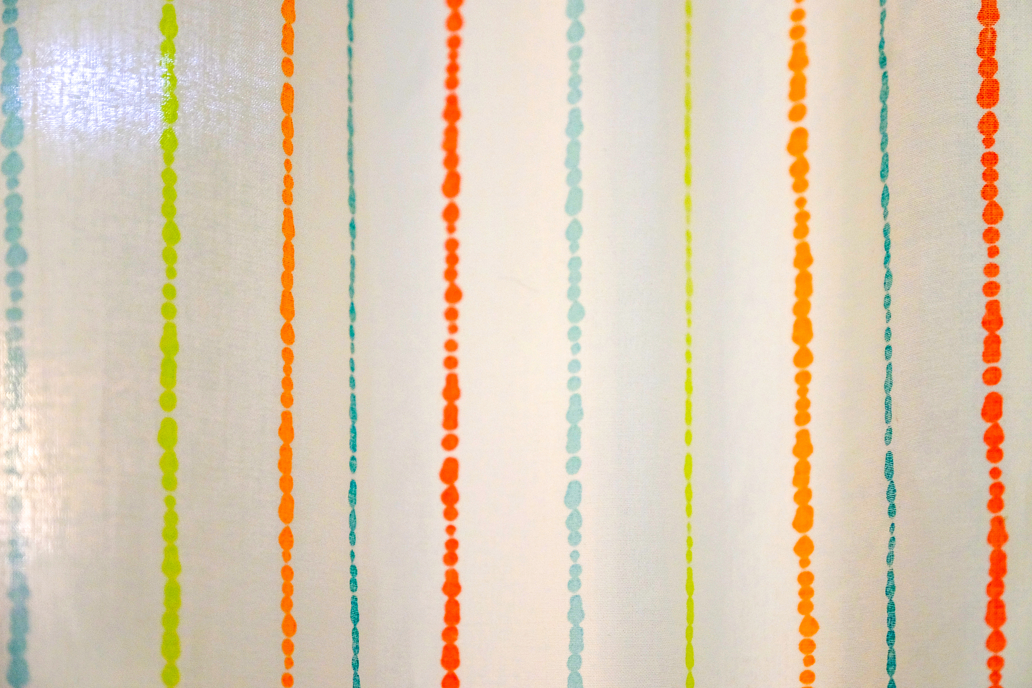 the curtain hangs on a horizontal bar. against the white wall.