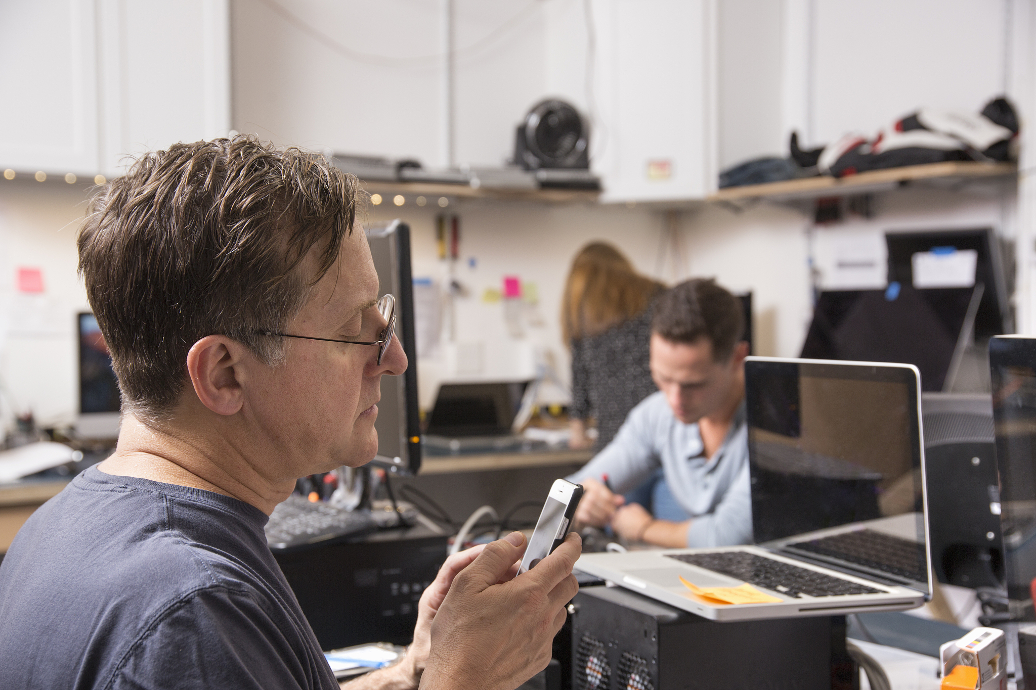 three people working in a technology lab, with a man in the fore