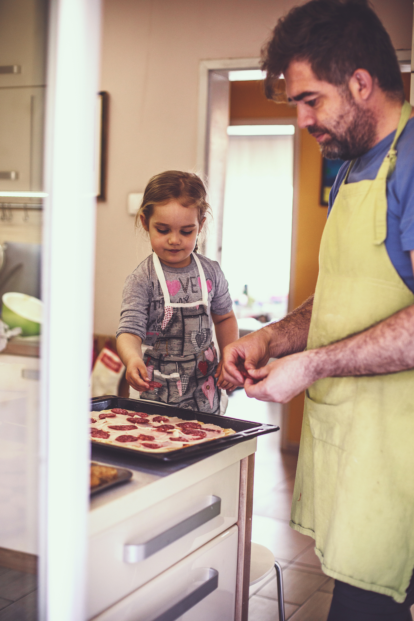 father and daughter making a homemade pizza together
