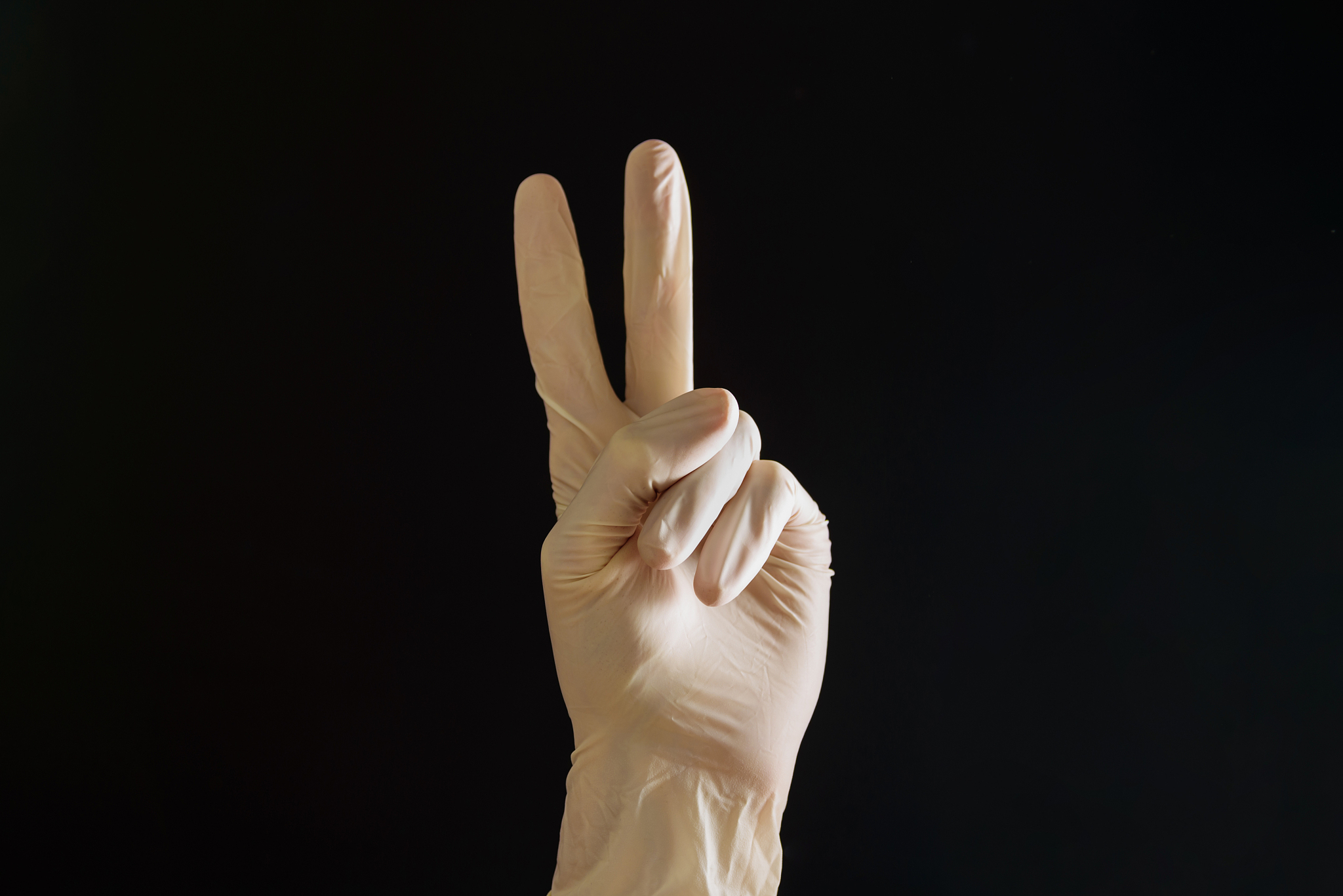 close-up of hand showing peace sign against black background