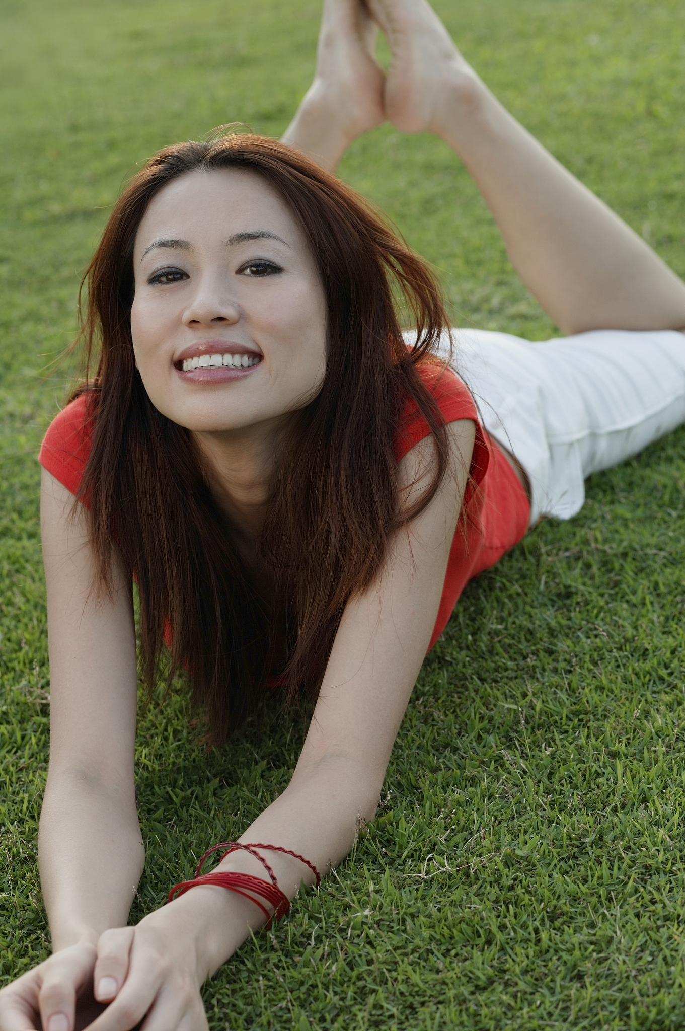 woman lying in park, smiling at camera