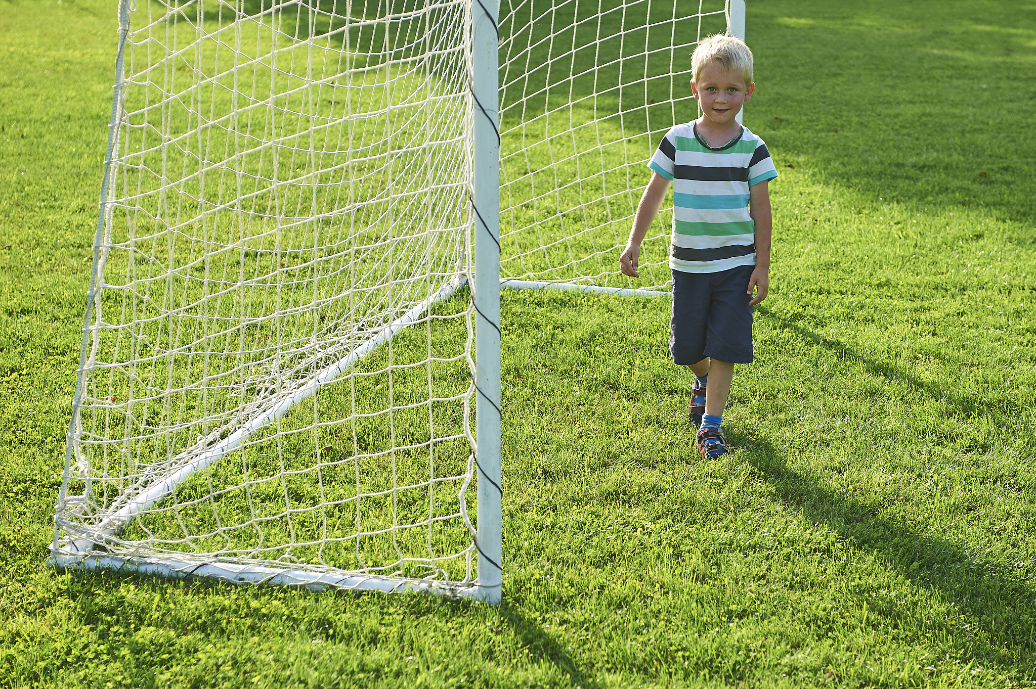 cute little blond boy playing at being a goalkeeper