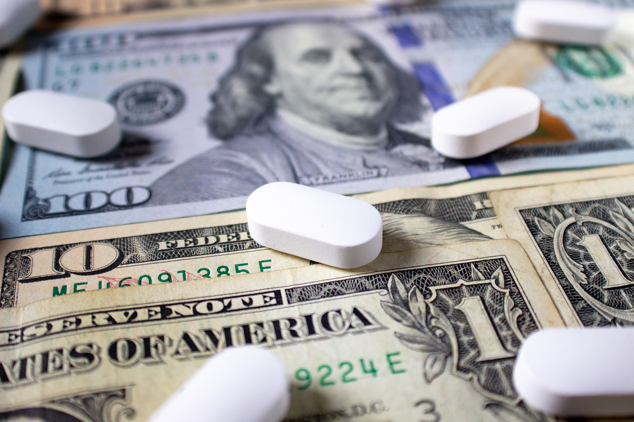 medicine and money. white pills on dollar bills one, ten and one