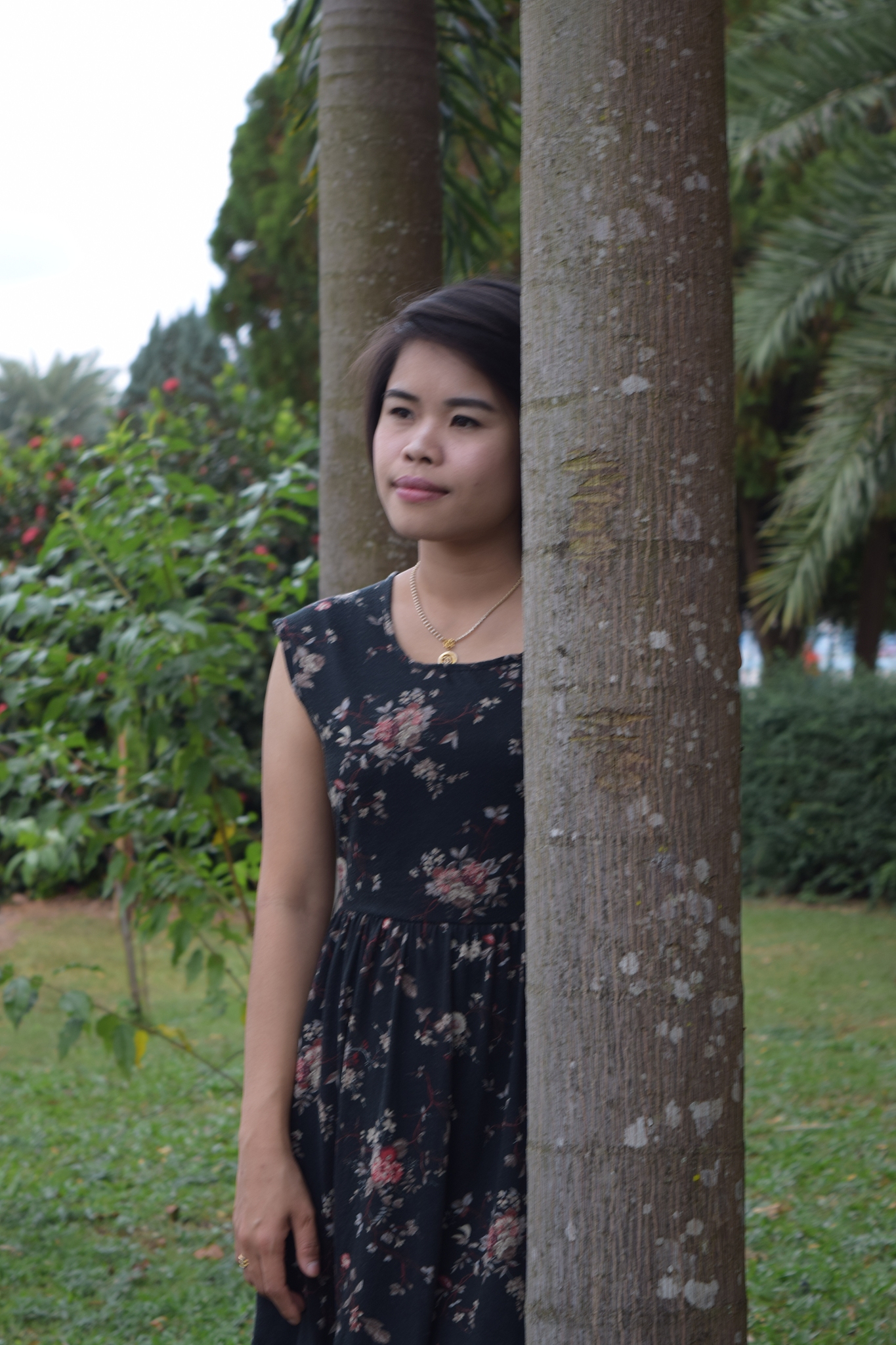 woman looking away while standing by trees